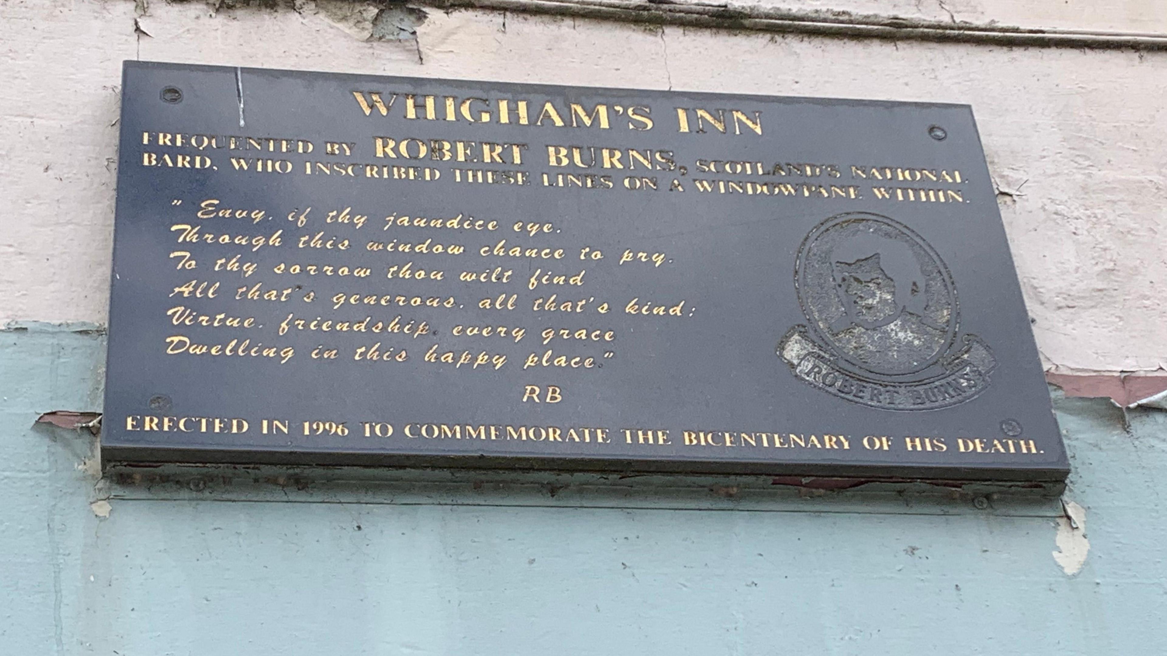 A plaque on the side of a building celebrating Robert Burns visits to the Whigham Inn and the poem he wrote about the site