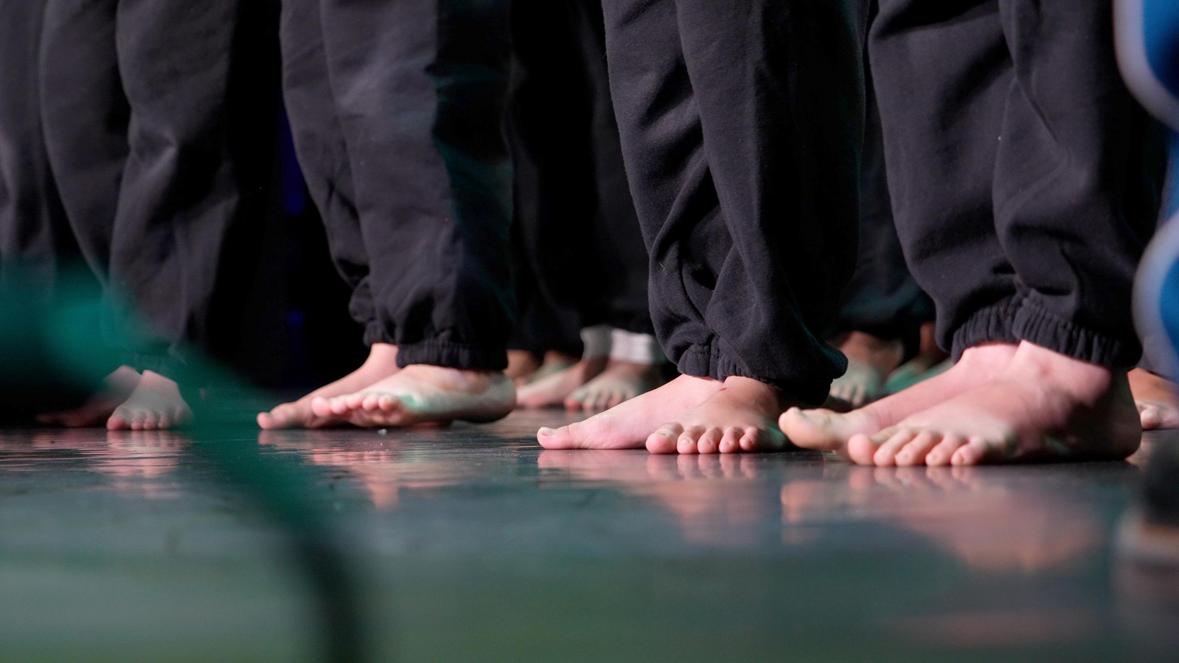 A group of bare feet on a black stage.