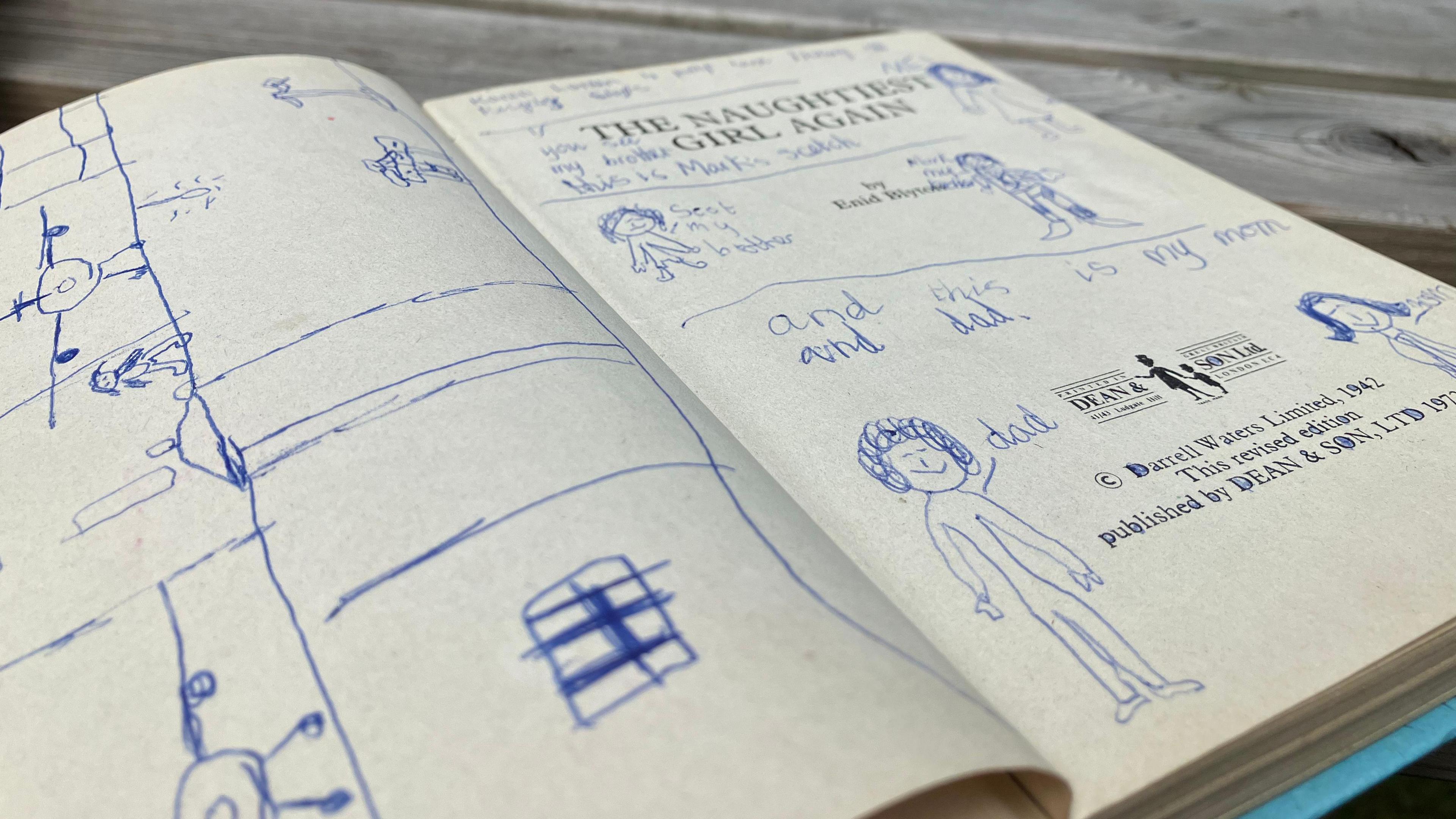 Drawings of people and writing in blue ink on the book.