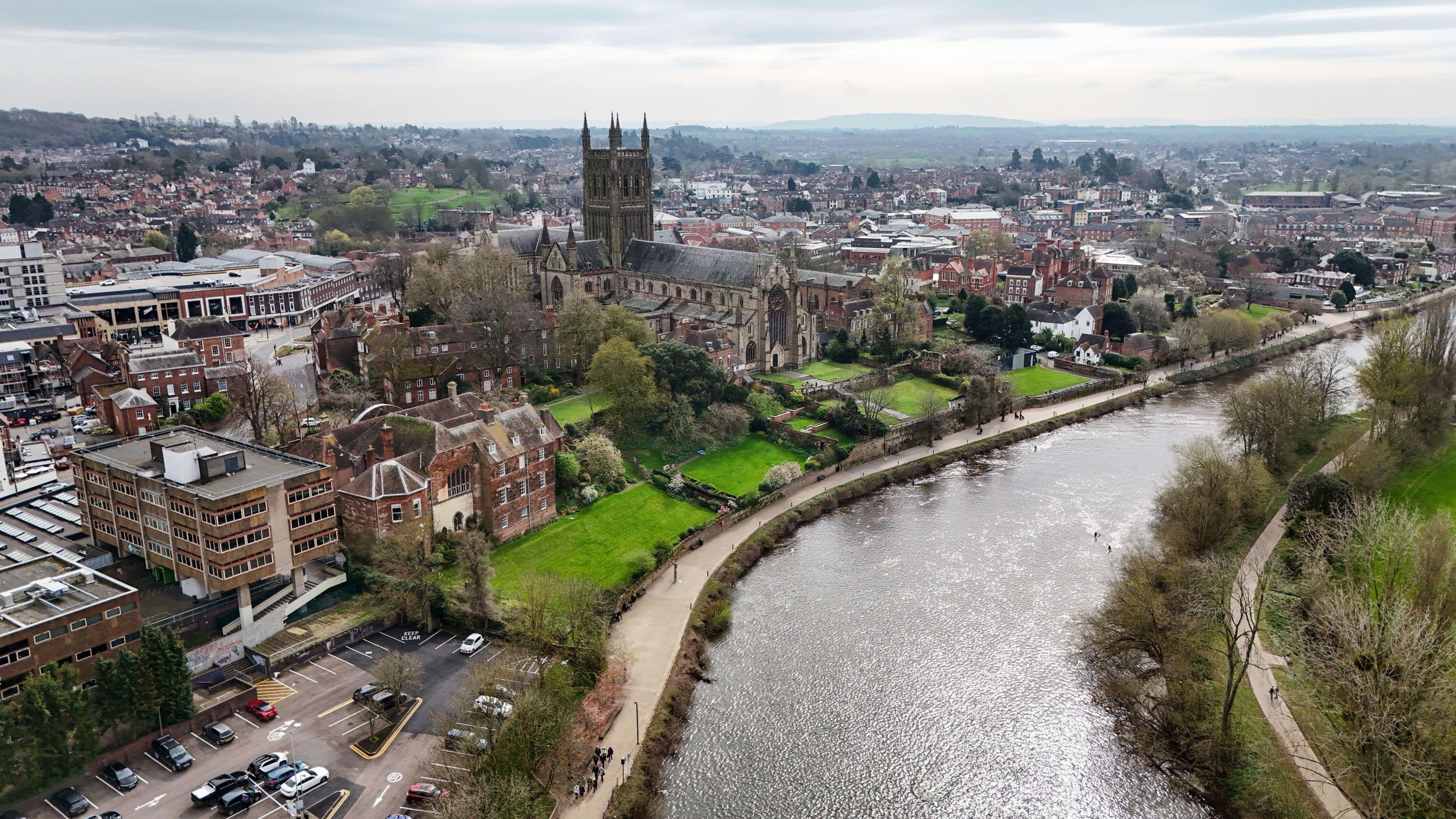 A drone shot above the River Severn in Worcester. Worcester Cathedral can be seen in the background as well as a number of other buildings throughout the city. 