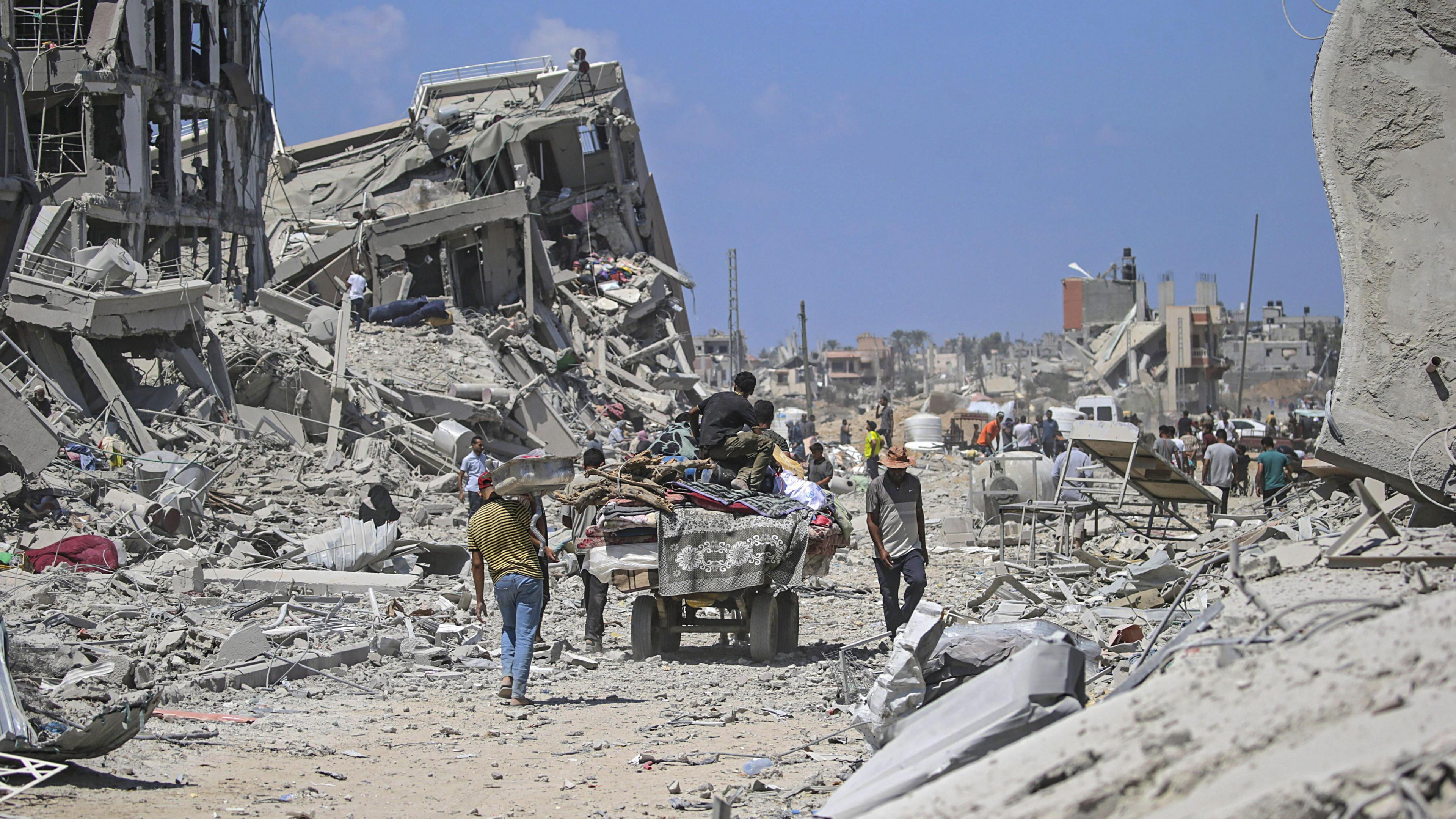 Displaced Palestinians walk through rubble in Gaza