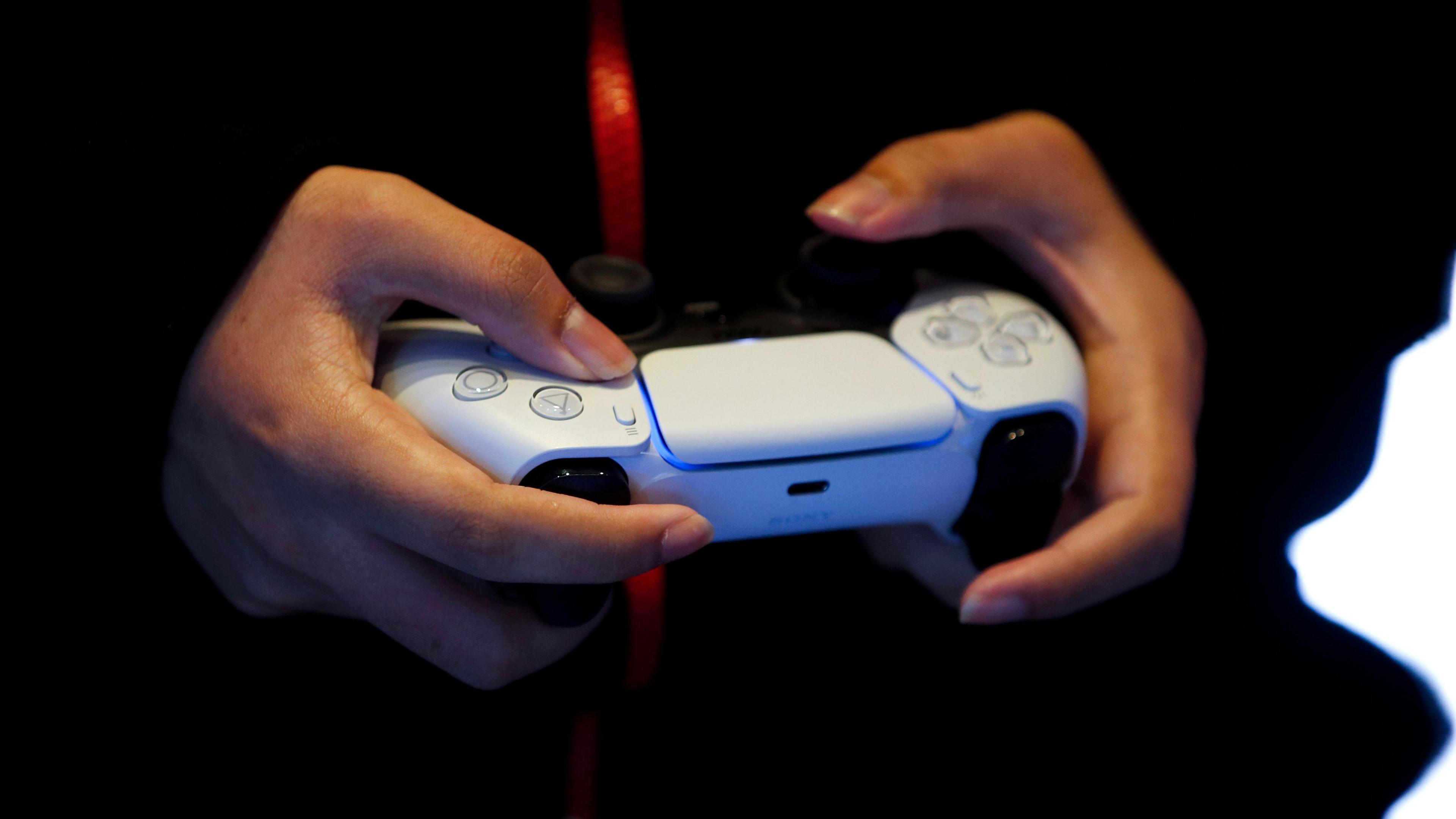 Hands playing on a PlayStation 5 controller