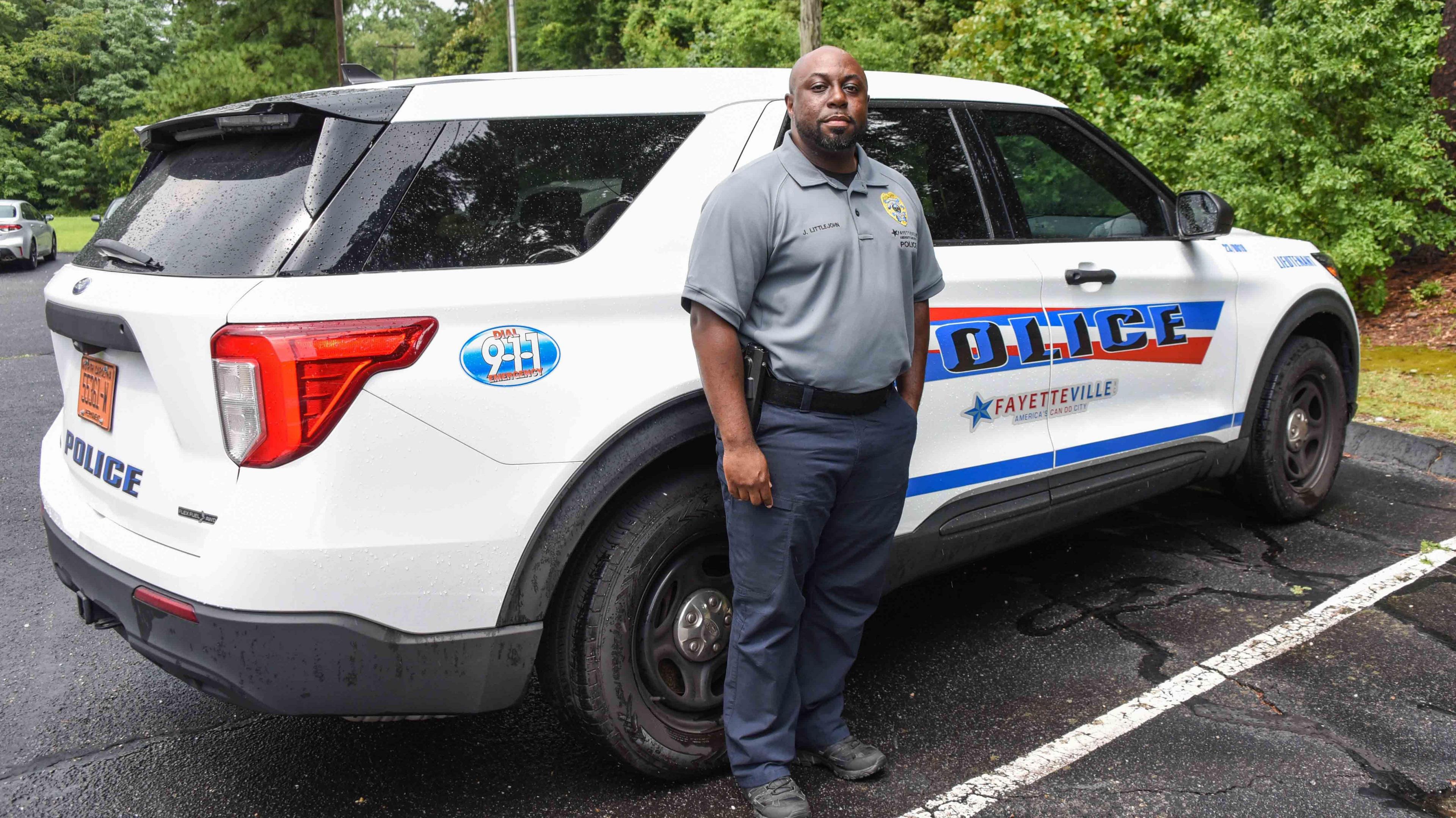 Ly Jamaal Littlejohn poses in front of a police car