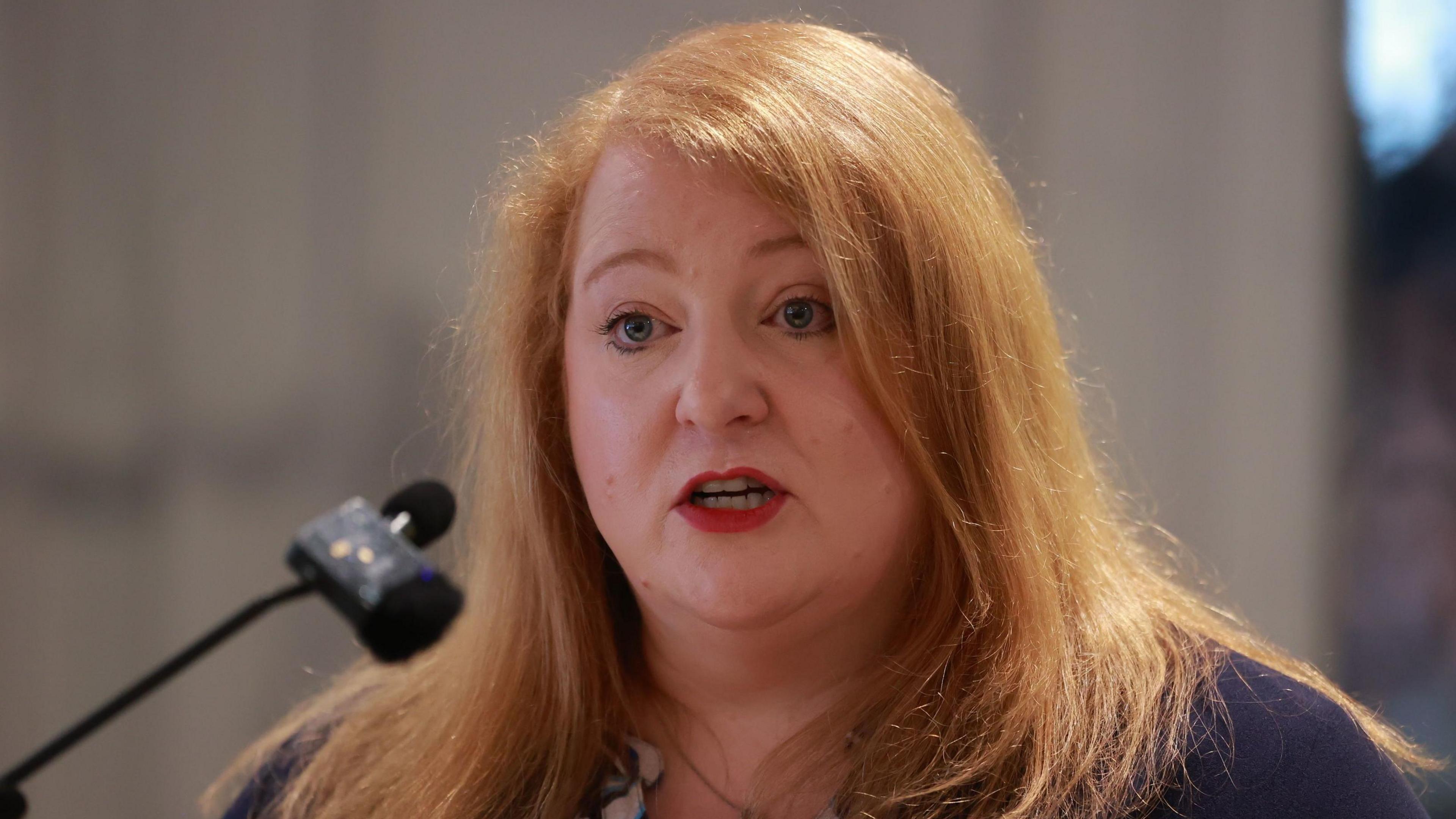 Justice Minister Naomi Long speaking at a microphone