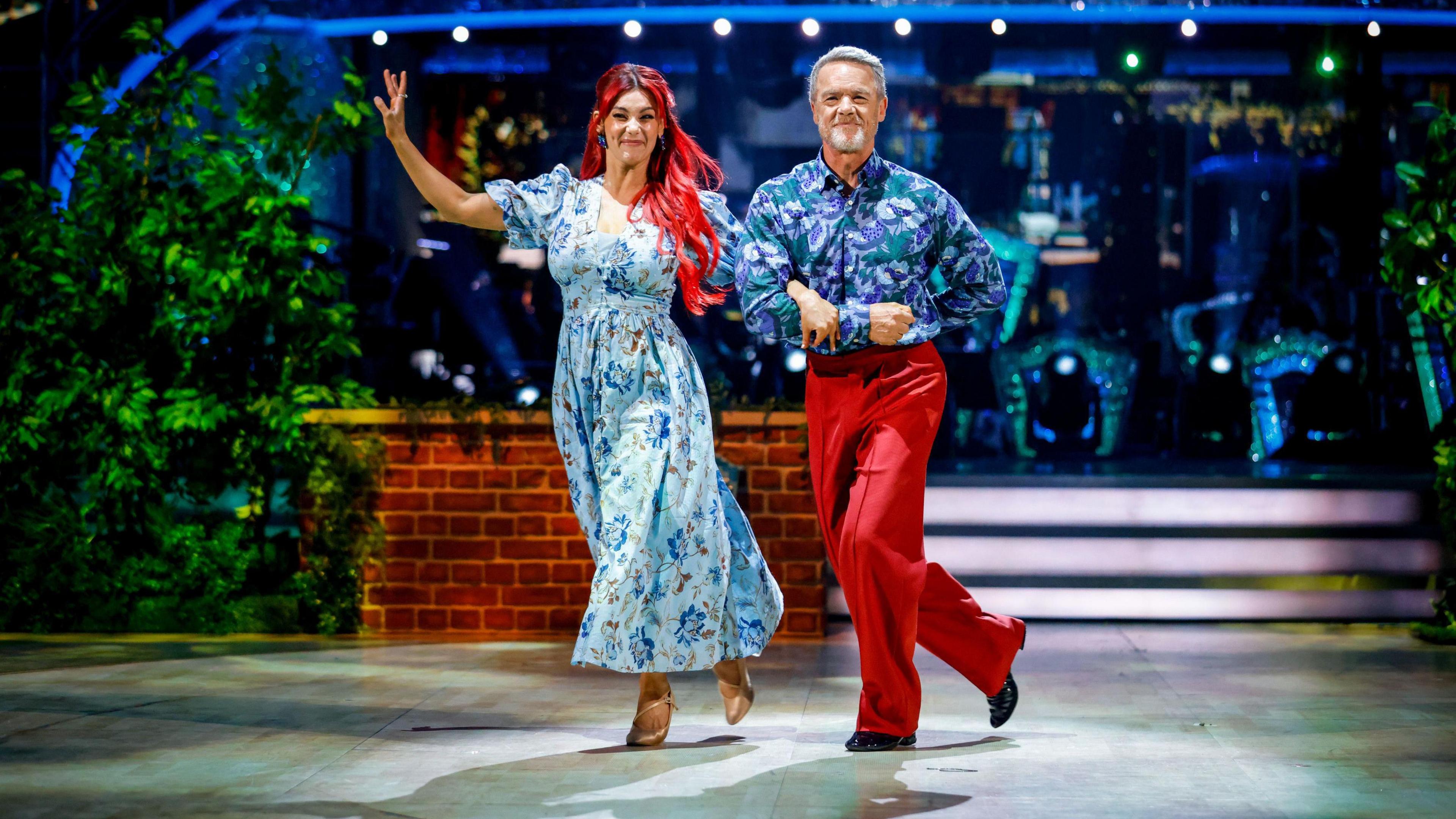 Dianne Buswell in a blue flowery dress dancing with Stefan Dennis in a blue patterned shirt and red trousers