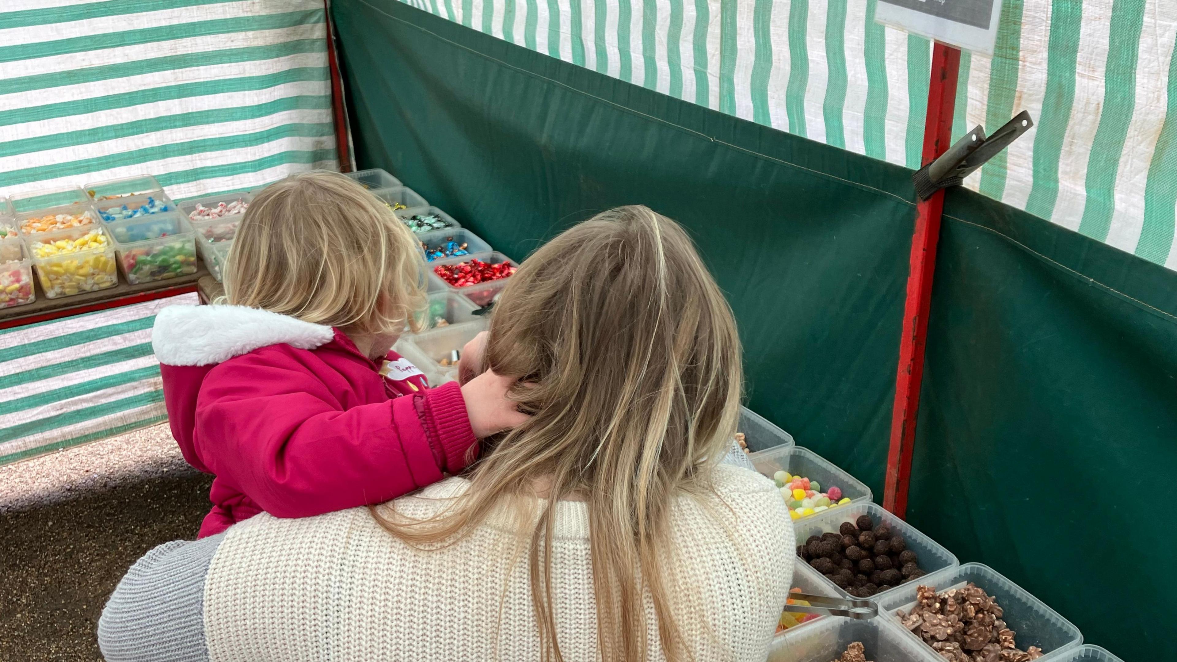 Mother and young daughter choosing sweets at the stall