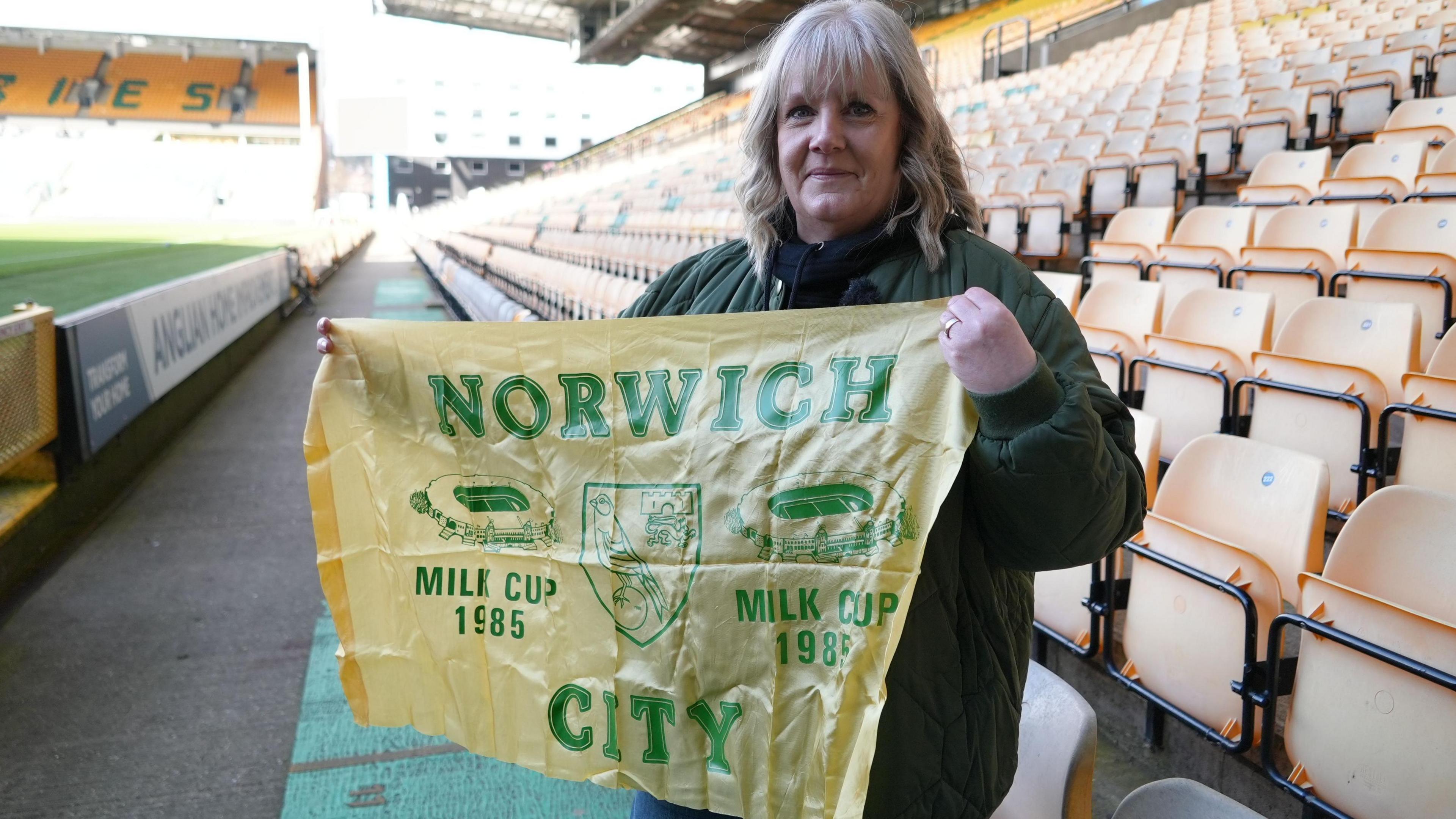 Lorraine Taylor holds aloft the Norwich flag she took to Wembley in 1985