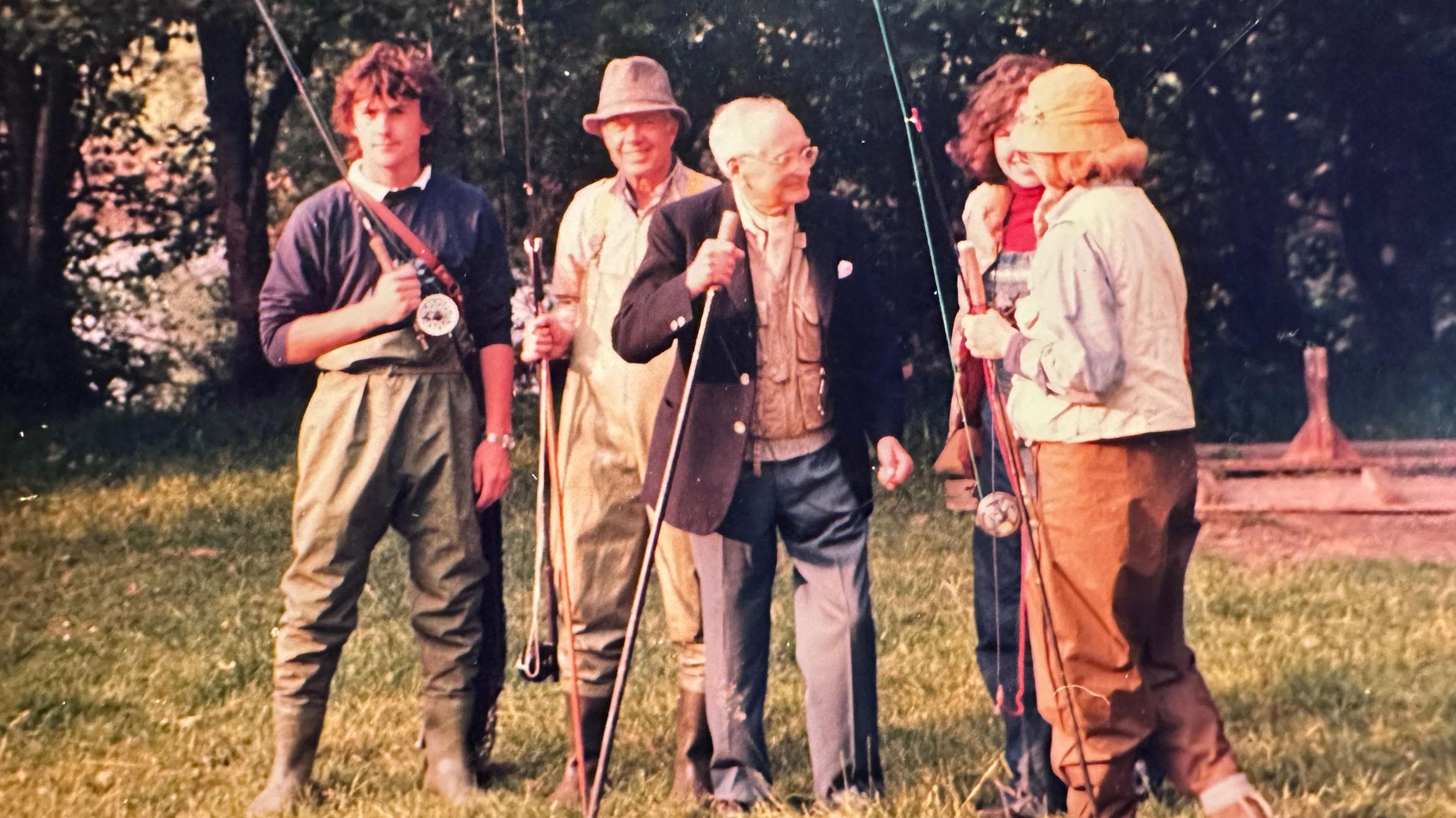 Group of five from the fishing party with rods in hand, chatting on the banks of the River Teifi.