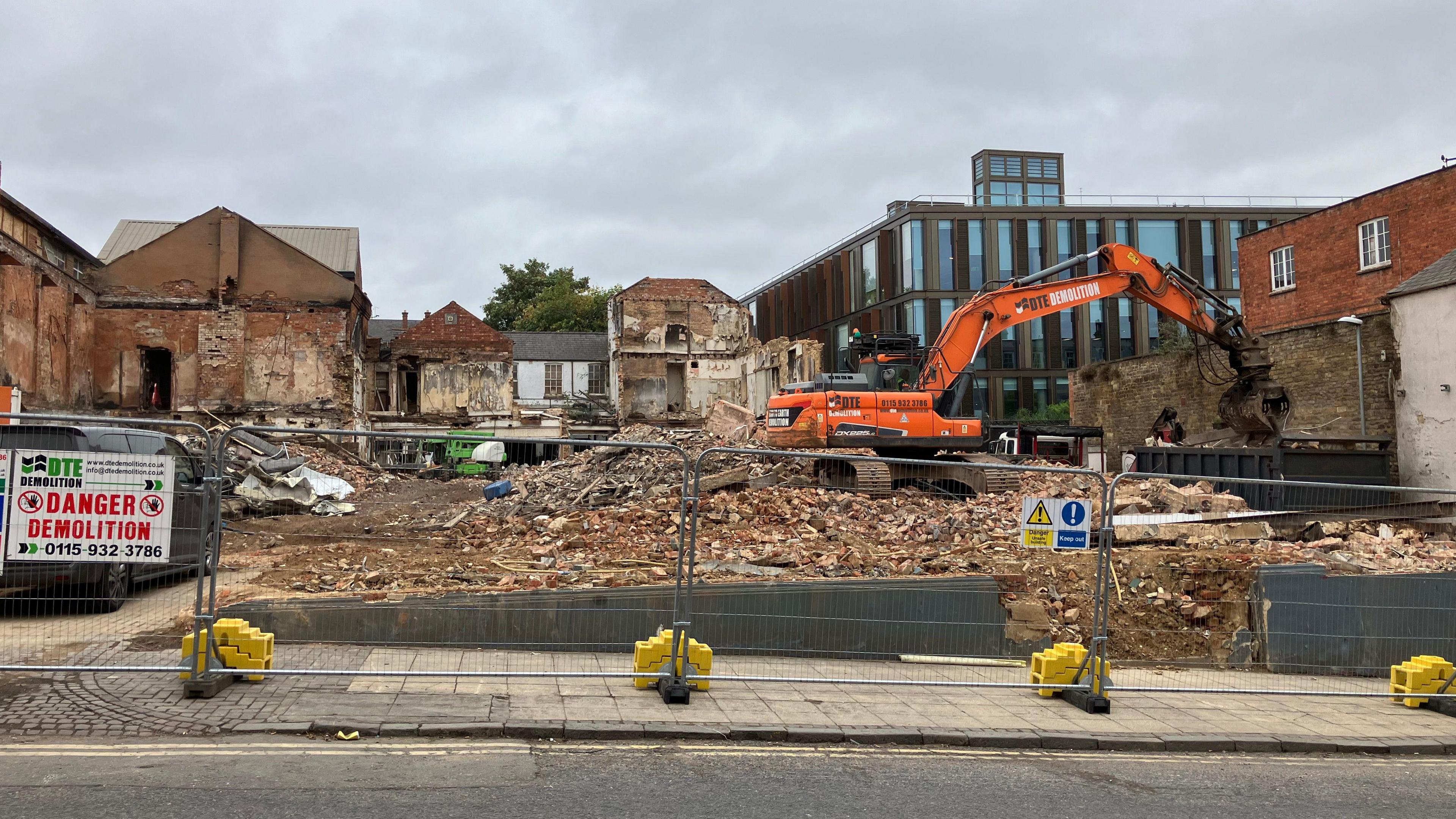 An orange digger taking apart the remains of the old hotel and bar site.