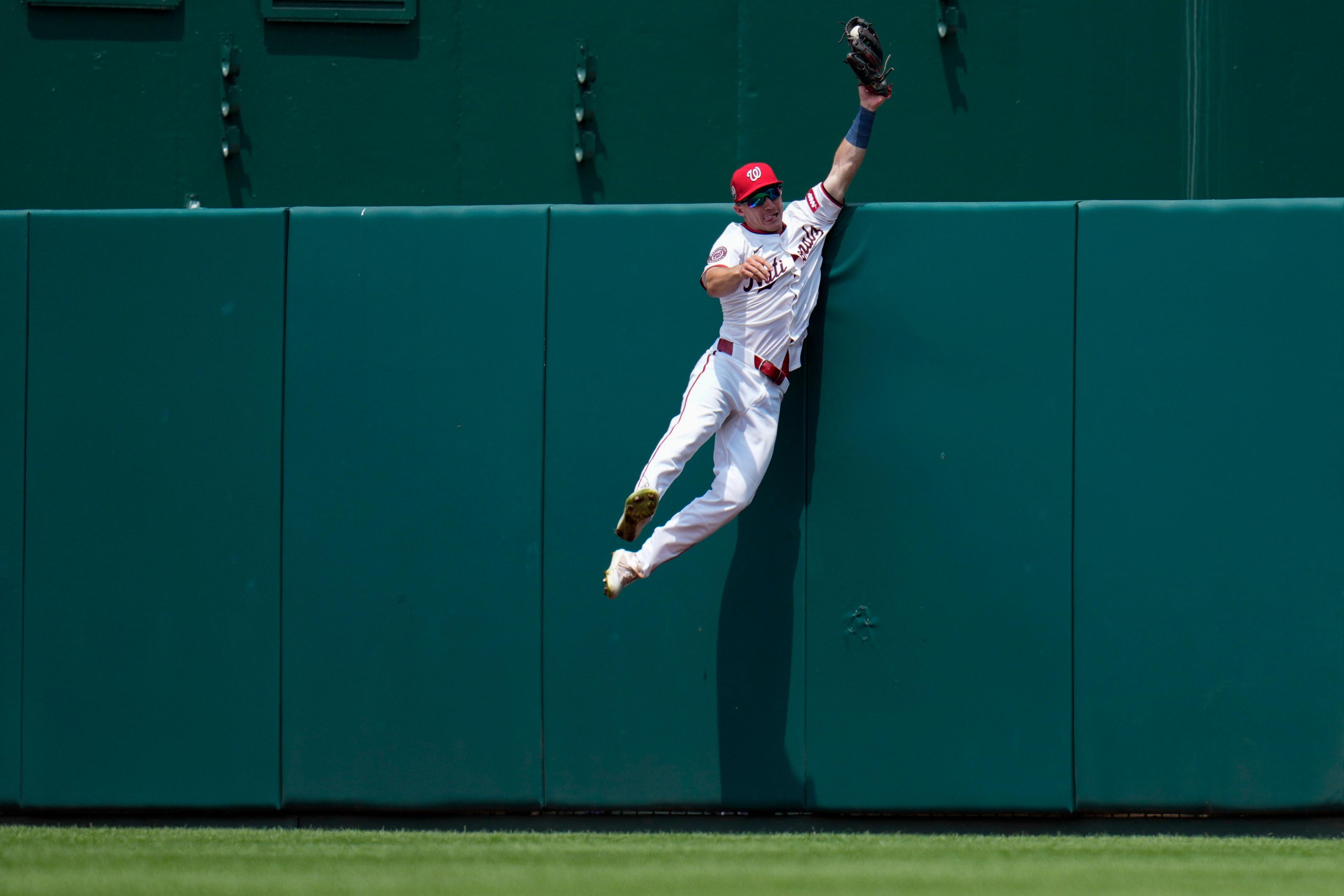 Washington Nationals' Jacob Young stretches up to catch a ball hit by Cincinnati Reds' Will Benson during the eighth inning at Nationals Park in Washington, DC. Photo by Jess Rapfogel