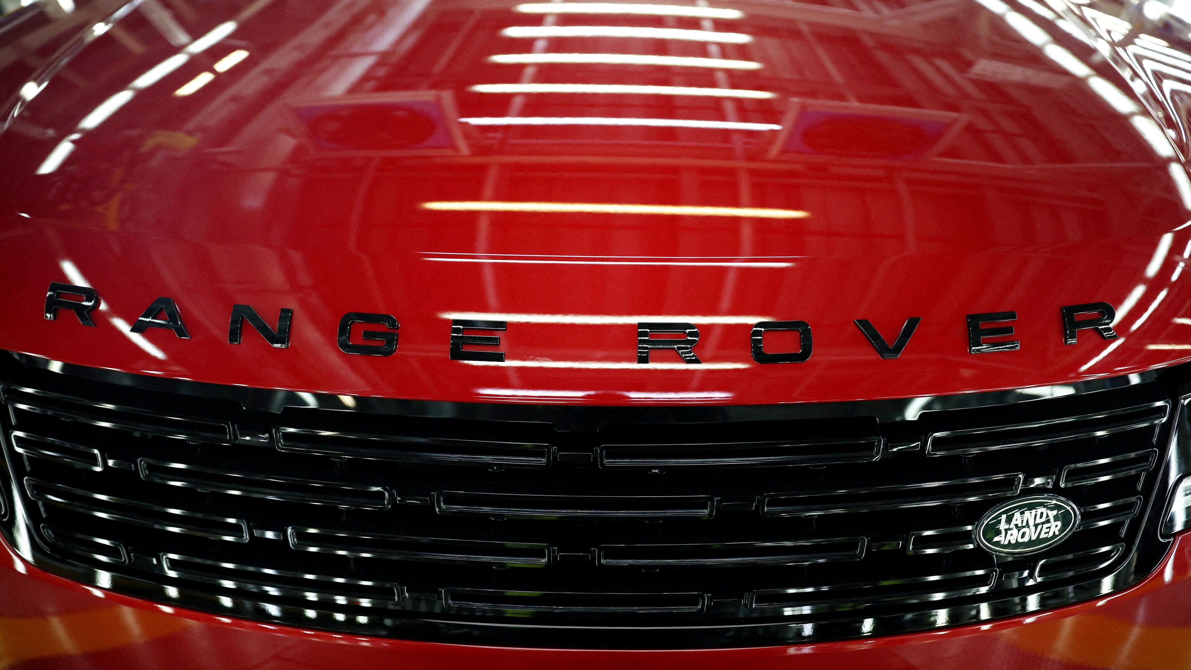 Close-up of the front of a red Range Rover, with the logo in black letters across the bonnet and a Land Rover badge on the radiator grille.