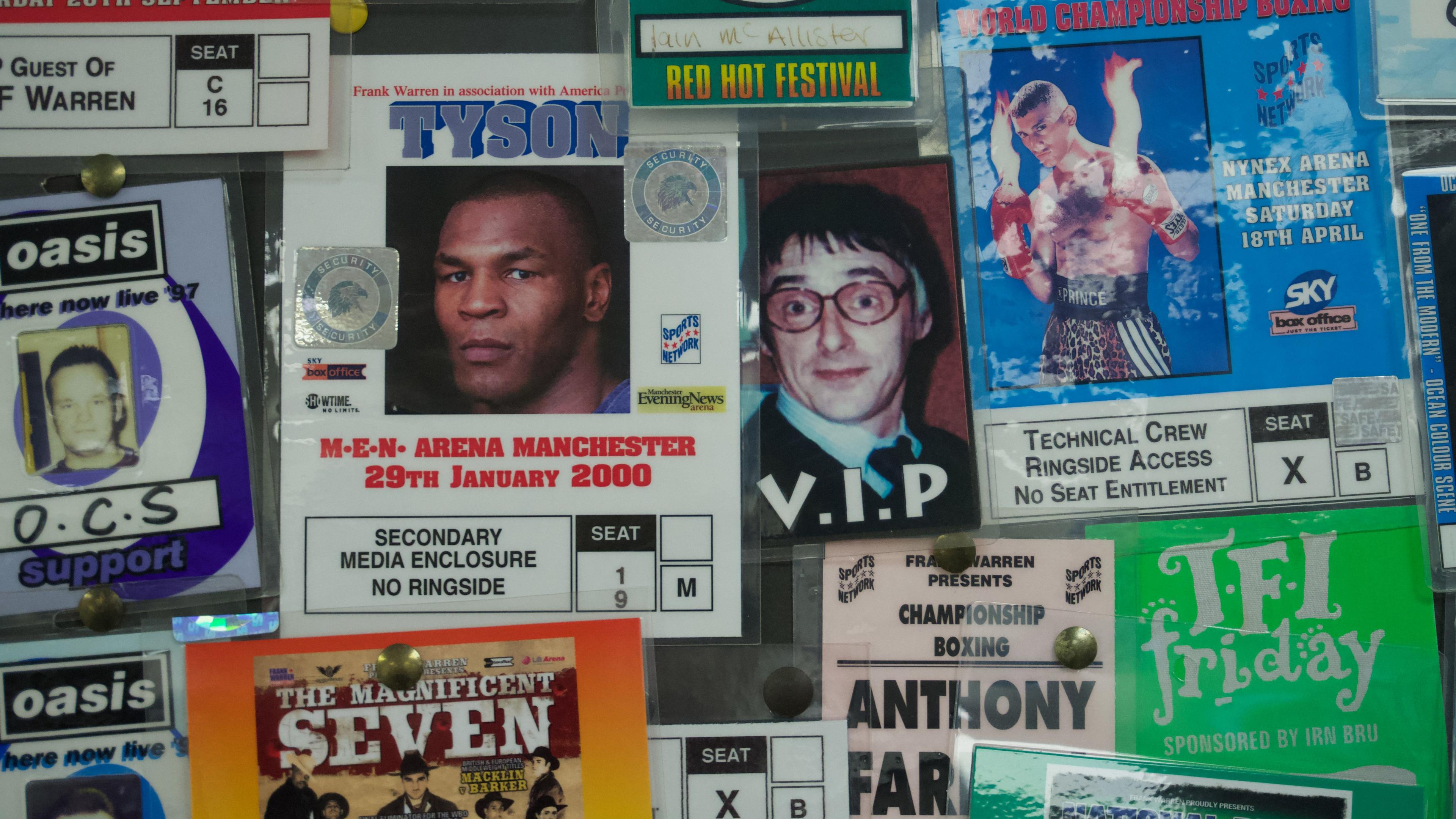 A close up of security badges for boxing and music events. The main one is a for a Mike Tyson fight in Manchester in January 2000. Next to it is a VIP pass for a Paul Weller concert, showing a photograph of the musician