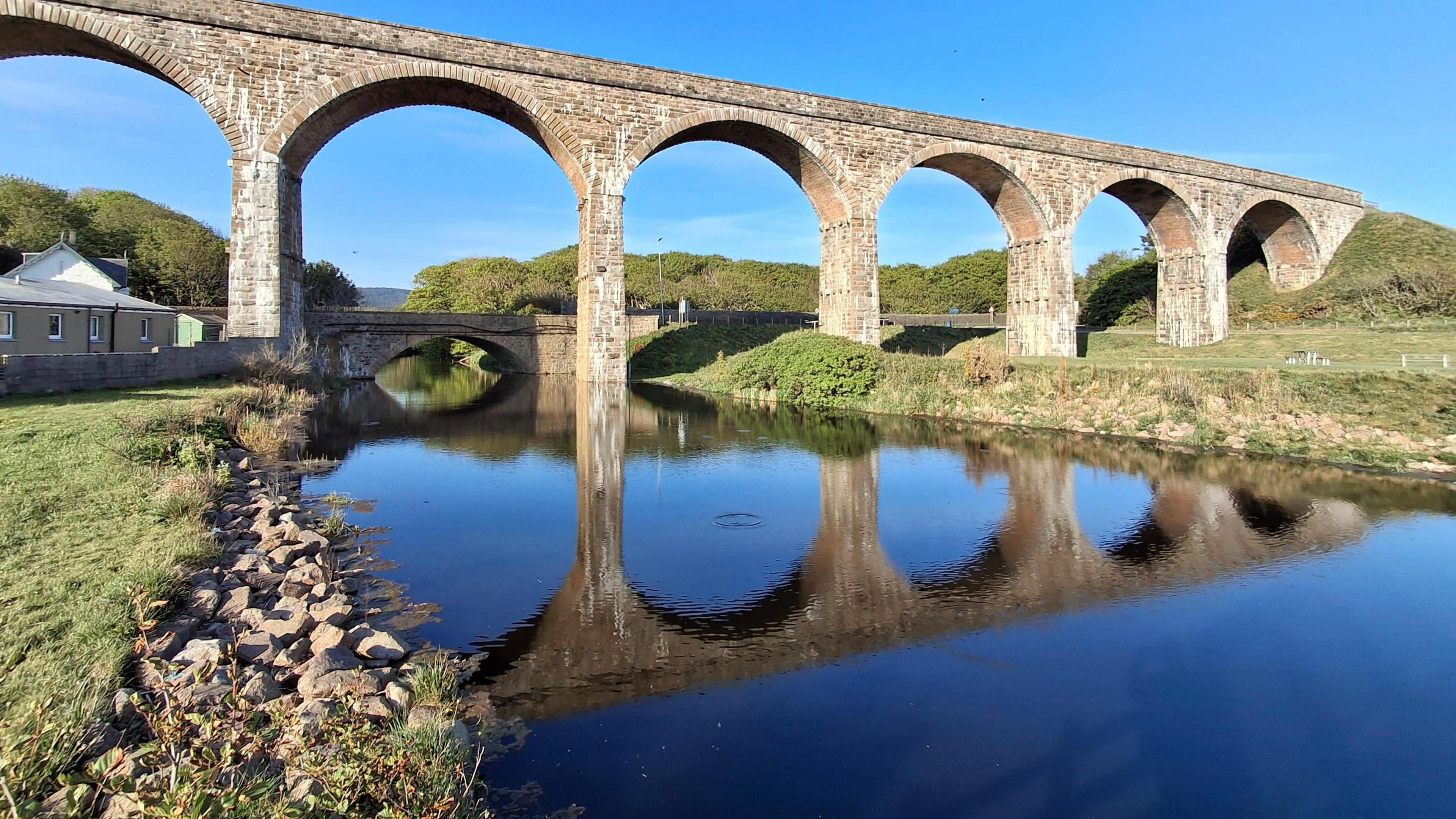 A stone viaduct over a river where the water level looks low