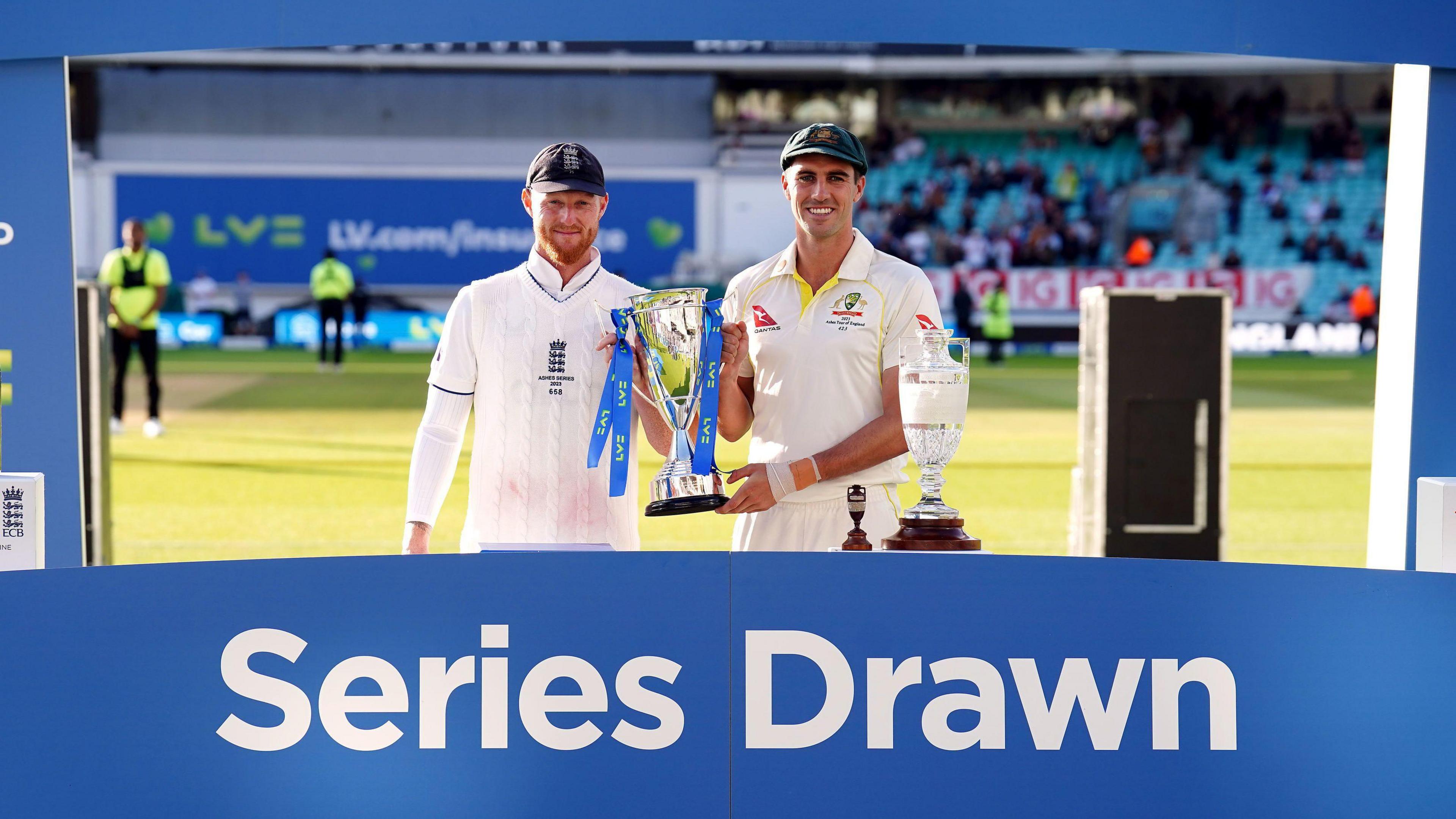 Ben Stokes and Pat Cummins standing next to a sign which says "Series Drawn" in 2023.