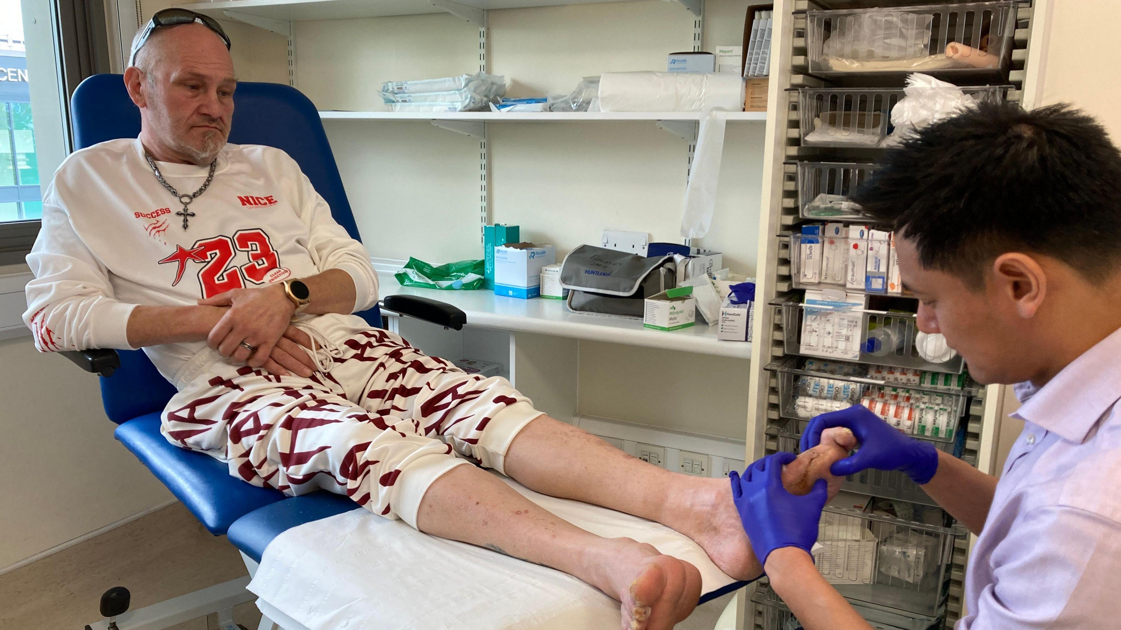 Mr Chan examines the foot of a diabetic patient lying on a bed