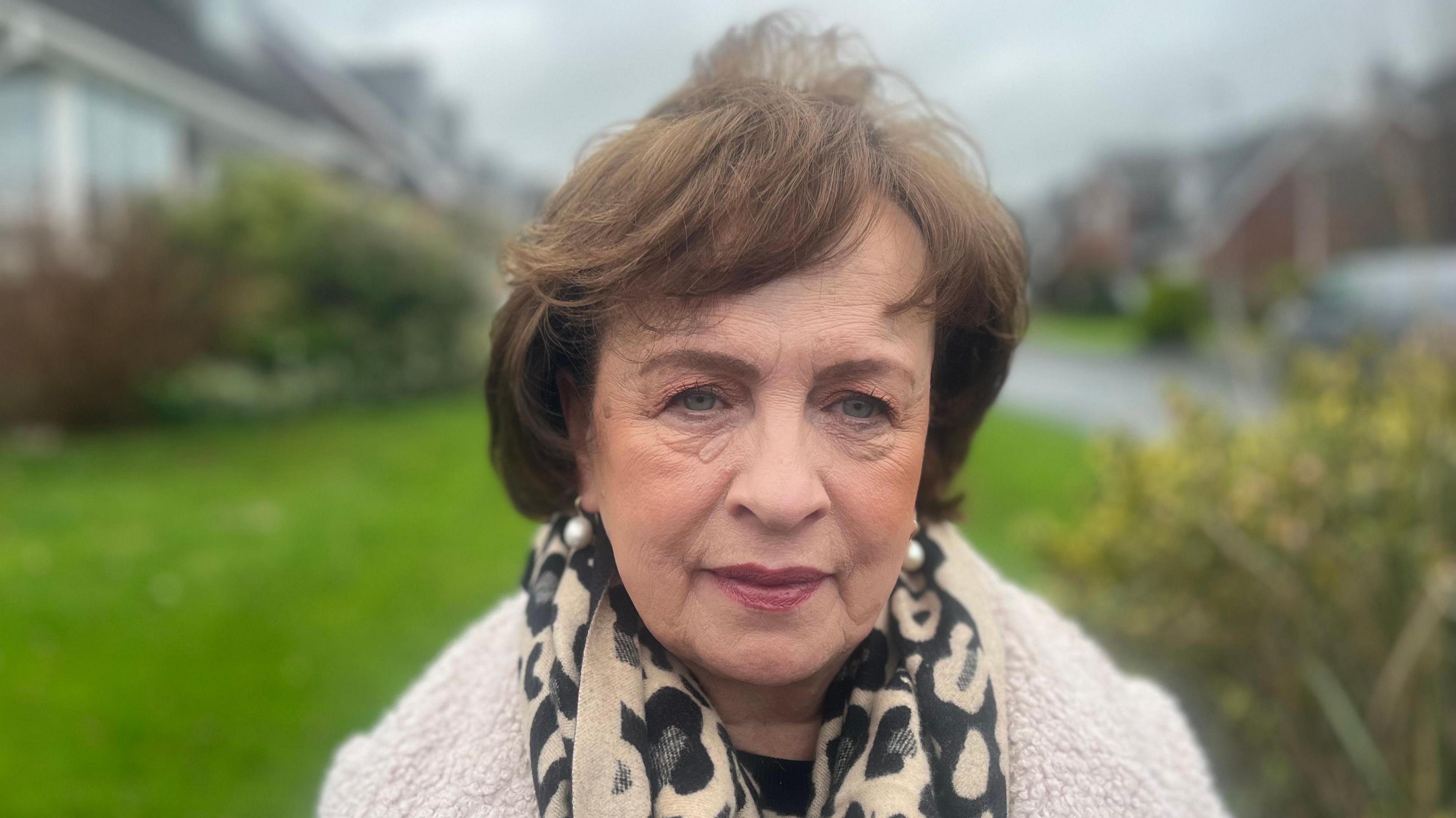 Diane Dodds is outside. She has short brown hair. She's wearing a scarf and a woolly jacket.