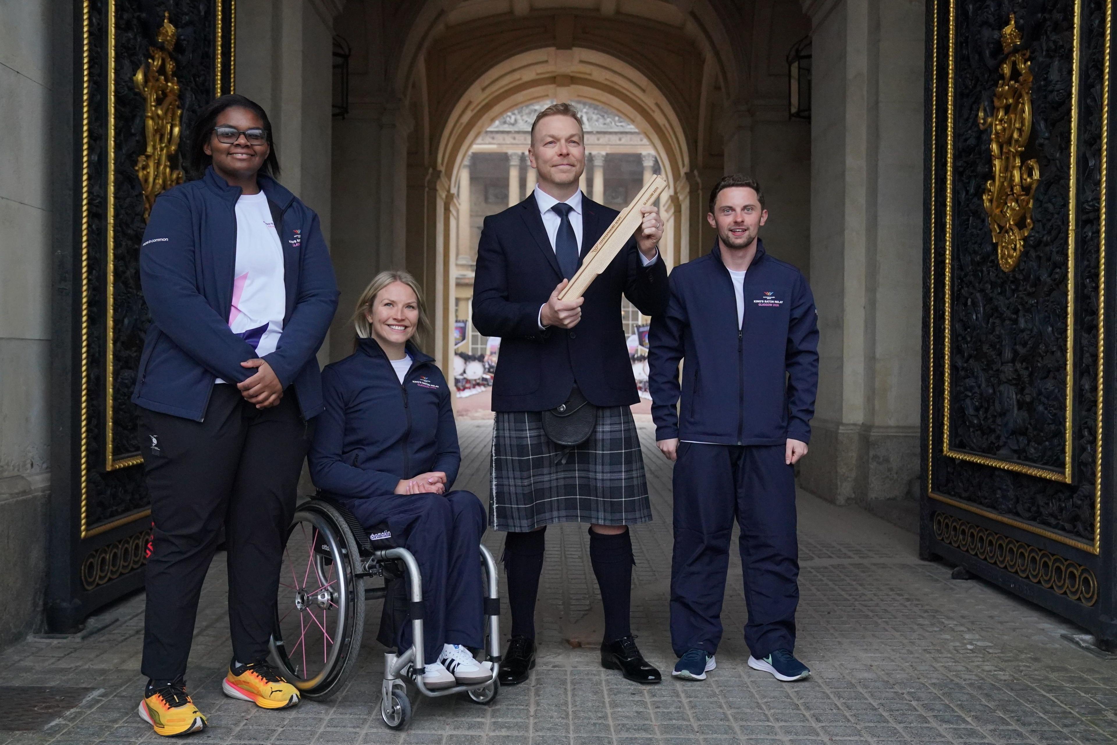 Chris Hoy stands holding a golden baton in a palatial looking courtyard while wearing a kilt, jacket and tie, while Gabriella, Sammi and Keiran smile next to him wearing Commonwealth tracksuits