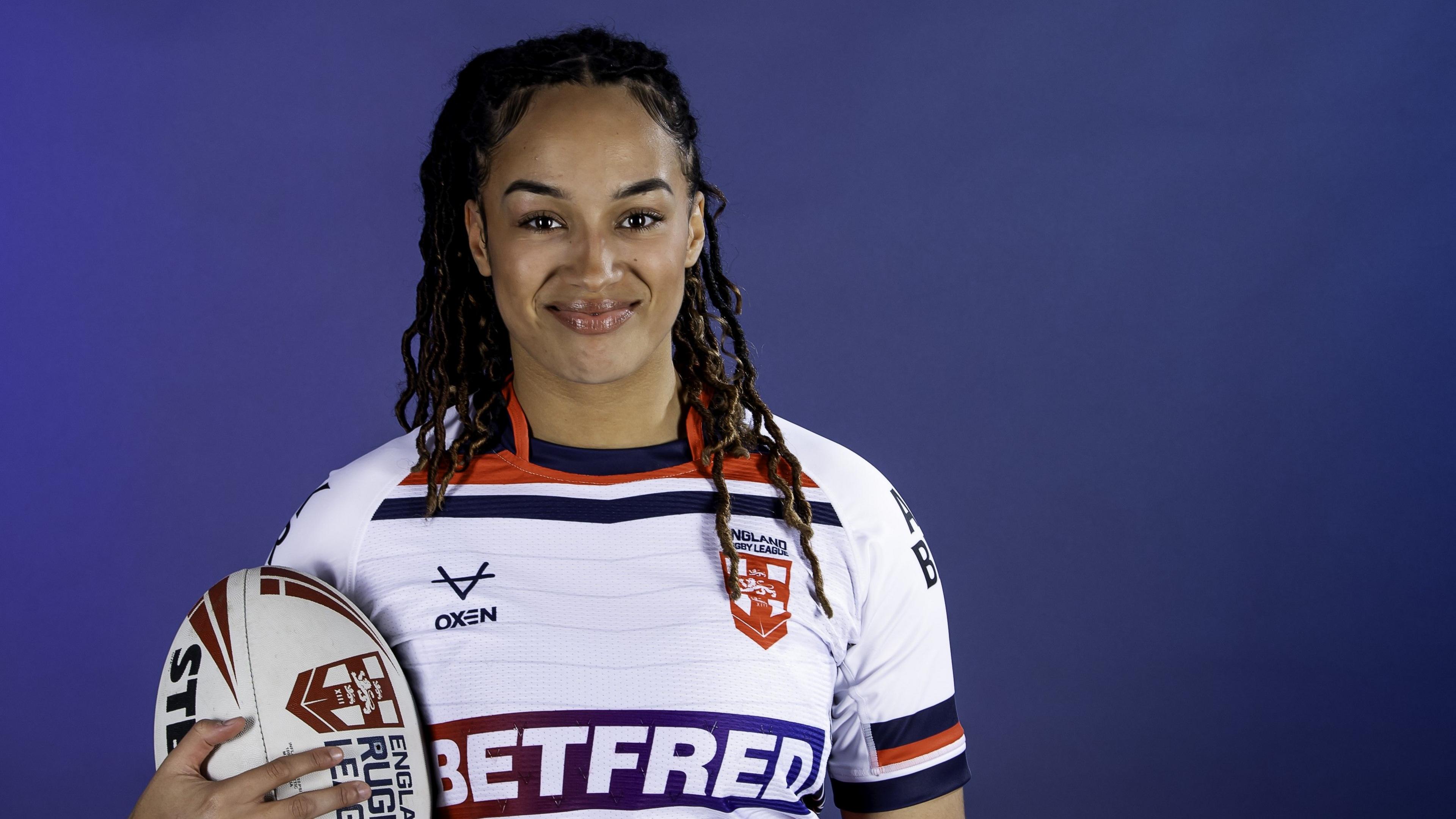 A smiling Amelia Brown holding a rugby ball