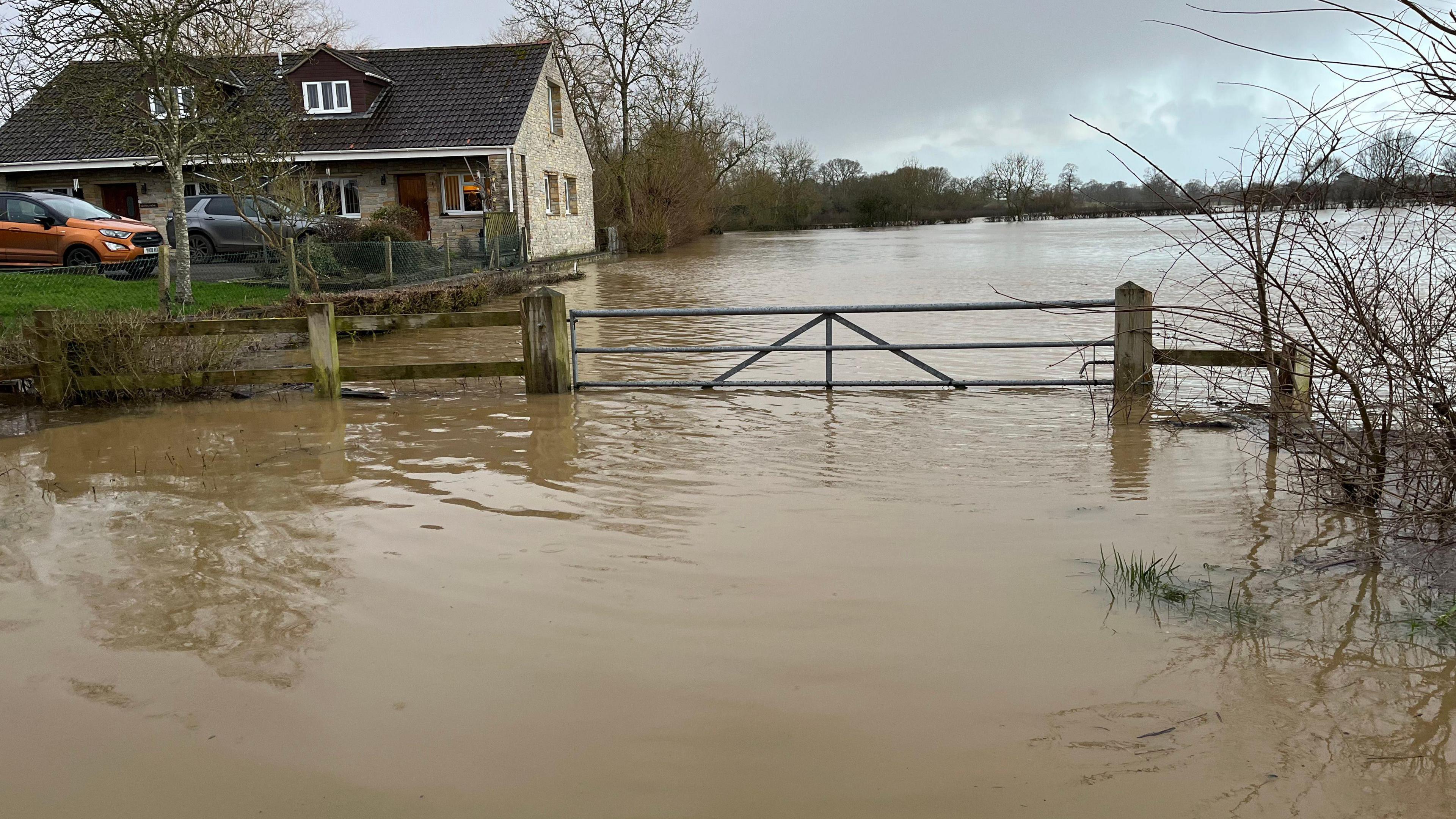 A flooded field with a house next to it.