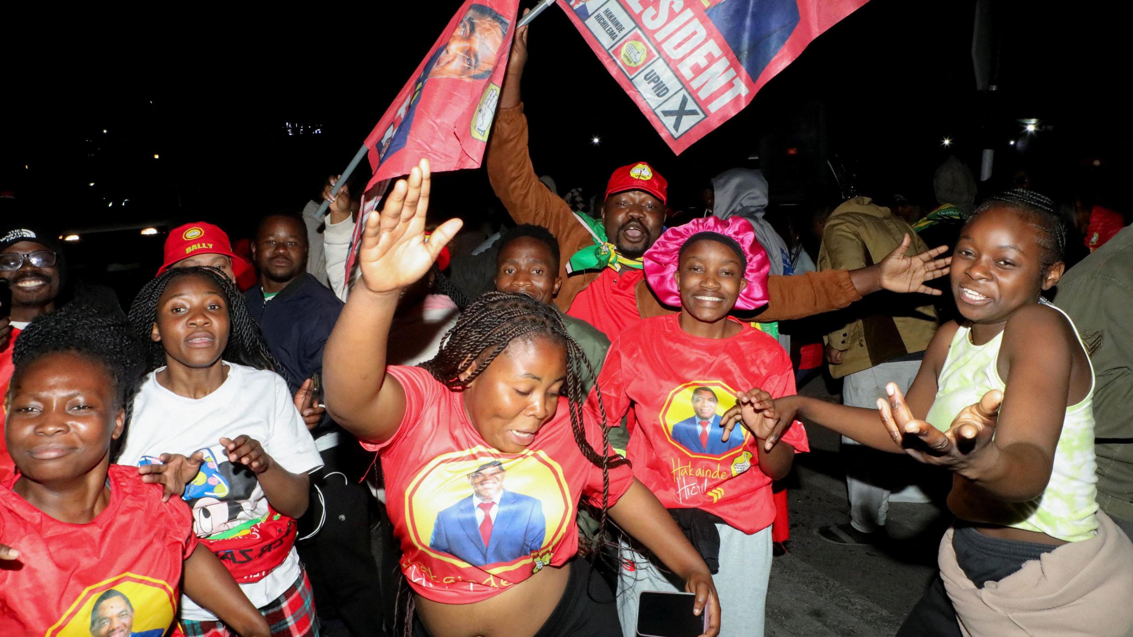 Supporters of Zambia's President Hakainde Hichilema dressed in red, celebrate after he was re-elected for a second term in Zambia's general election in Lusaka, Zambia