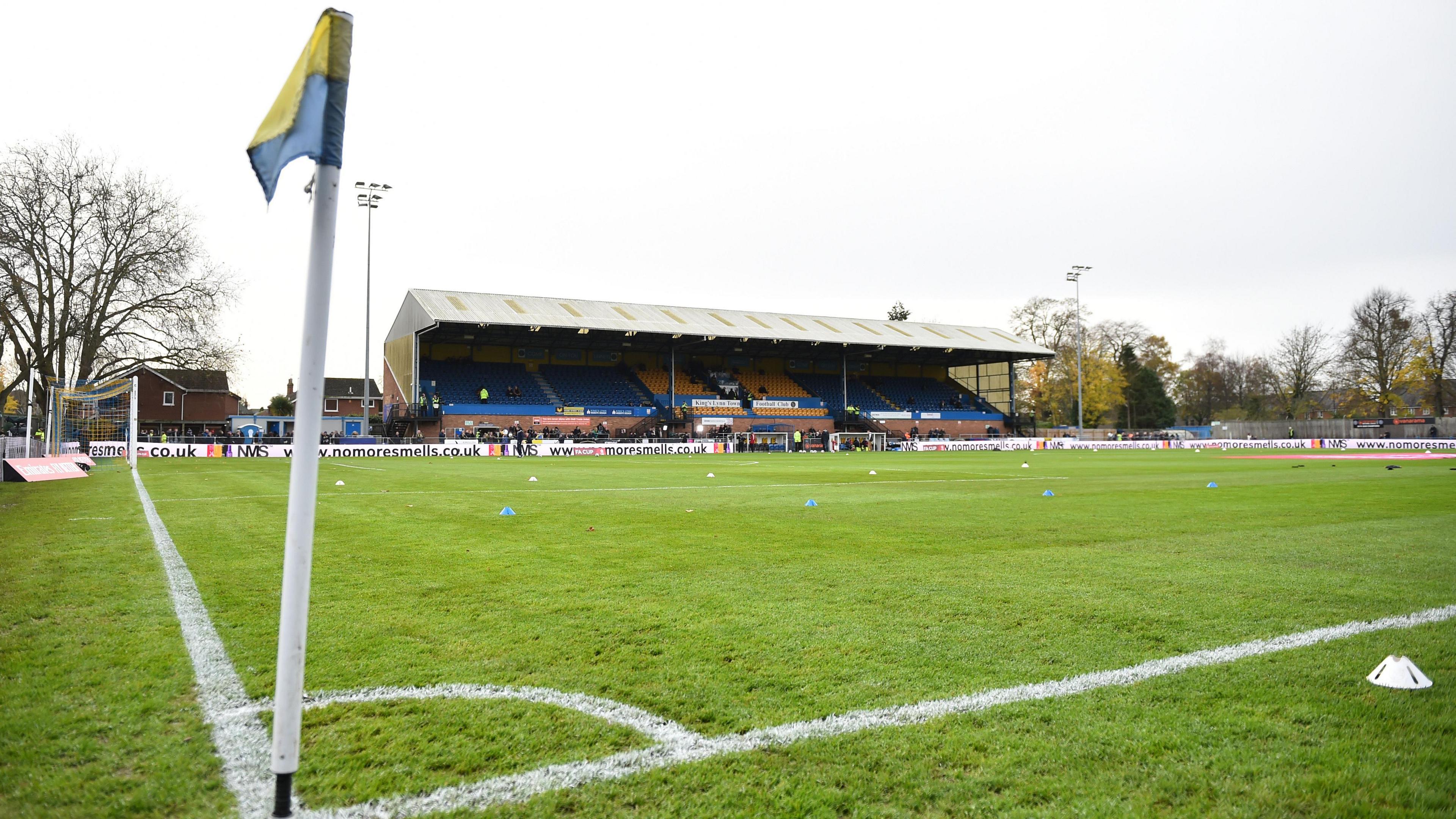 The Walks Stadium in King's Lynn where King's Lynn Town FC trains. In the picture is a green pitch with spectator stands.
