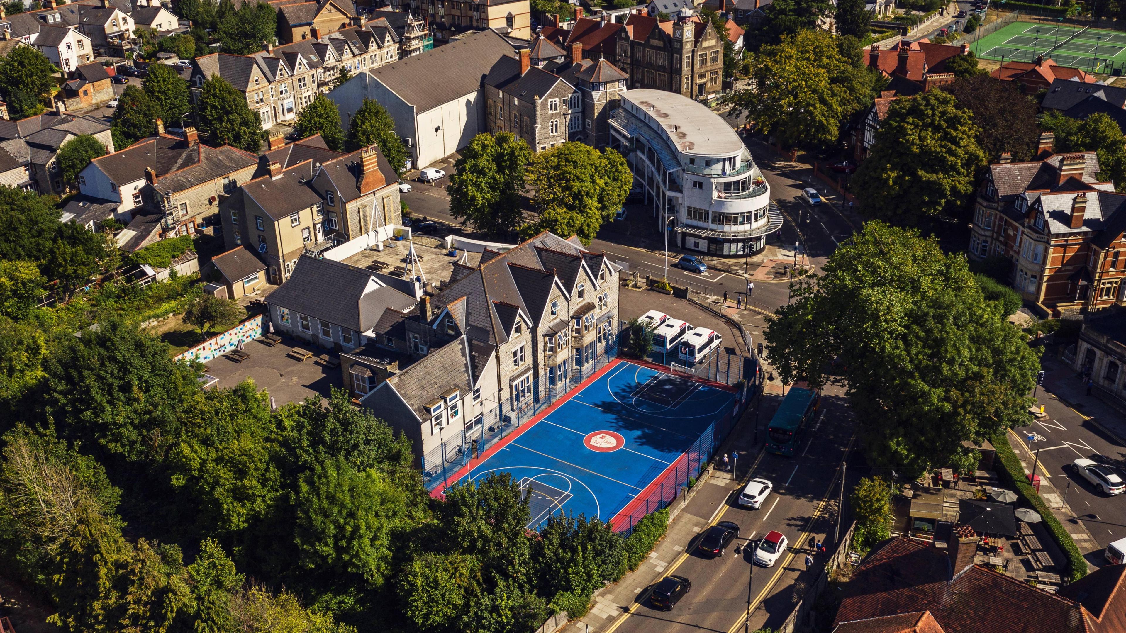 Westbourne School in Penarth and its large sports pitch shot from above. It is a large brick building surrounded by trees and roads.