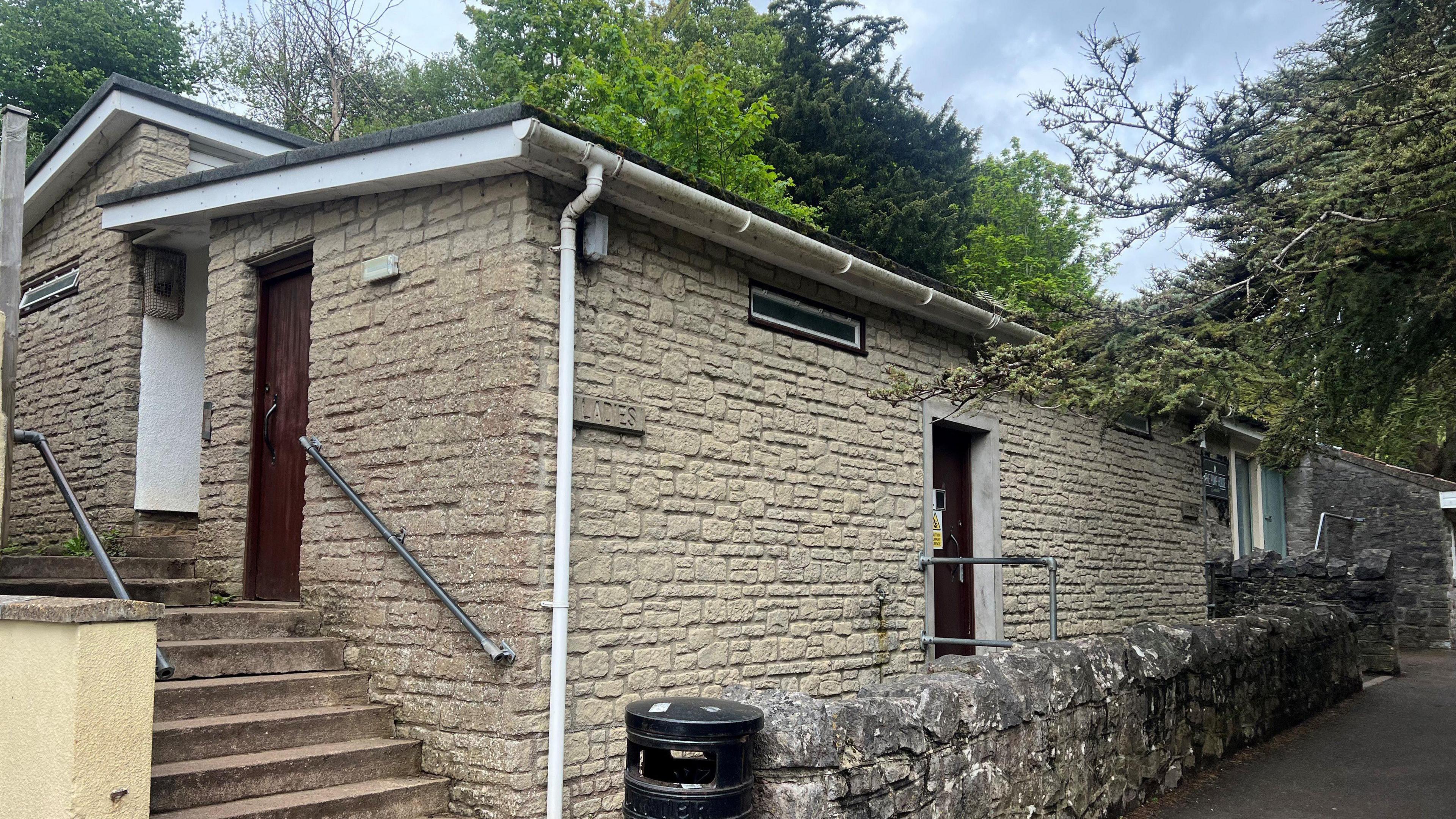 Old and grey toilet block with 'Ladies' and 'Gents' sign