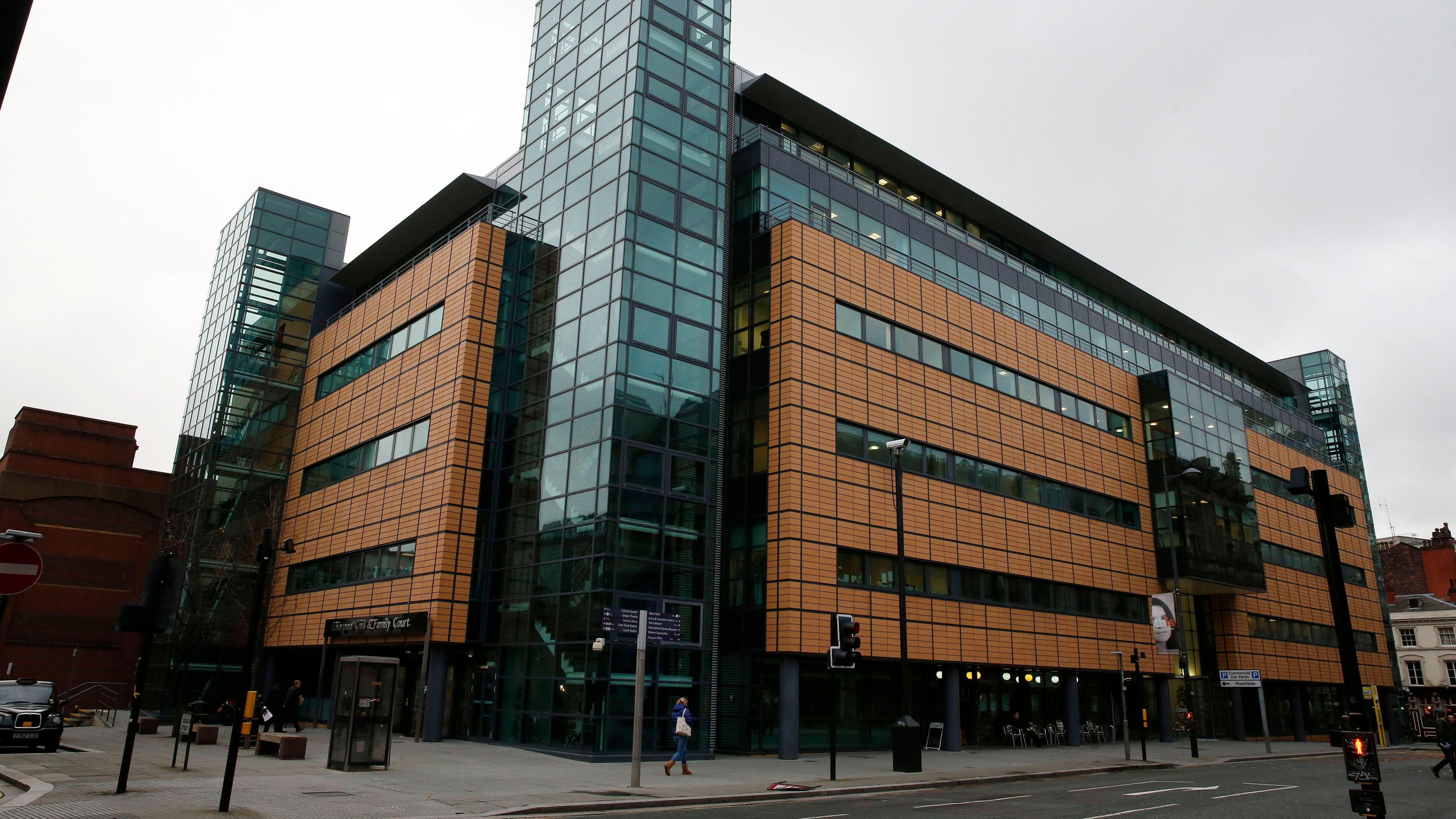 An exterior view of the Liverpool Civil and Family Court centre, which has salmon coloured cladding and glass panelled stairwells.