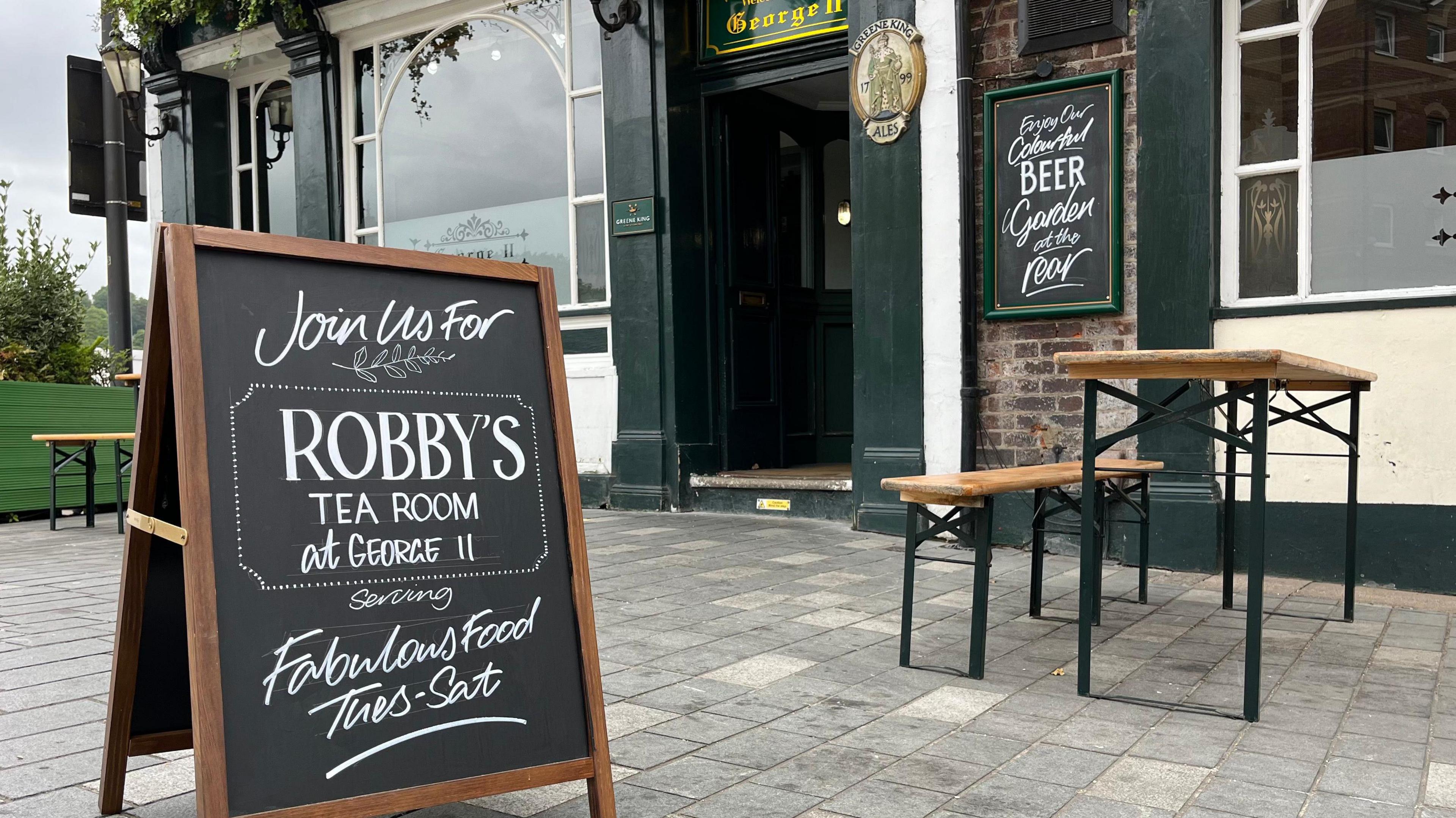 The outside of a pub with a board outside which says Robby's Tea Room