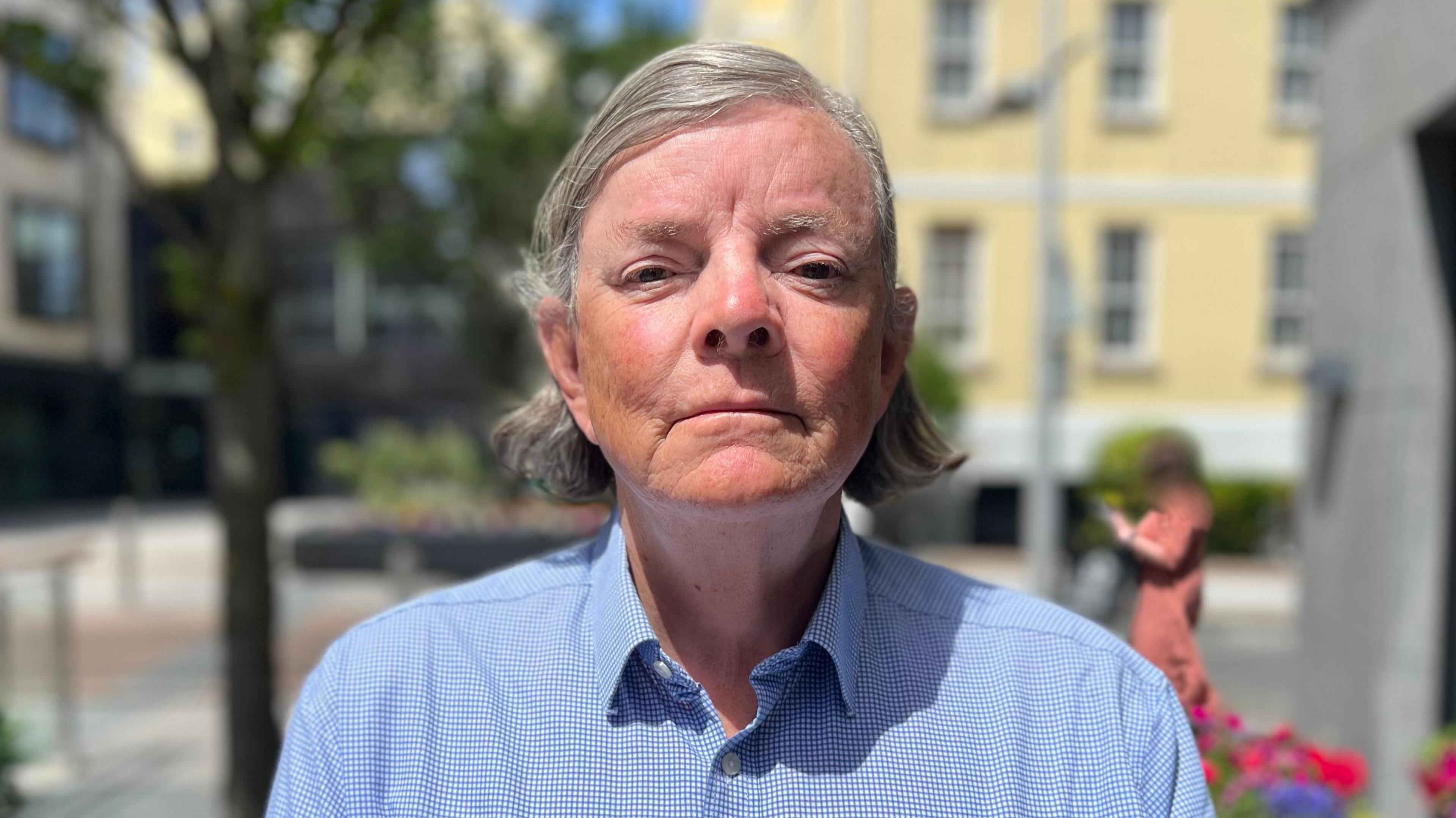 Deputy Charles Parkinson - A man with grey and black hair curled behind his head. He is wearing a blue shirt. 
