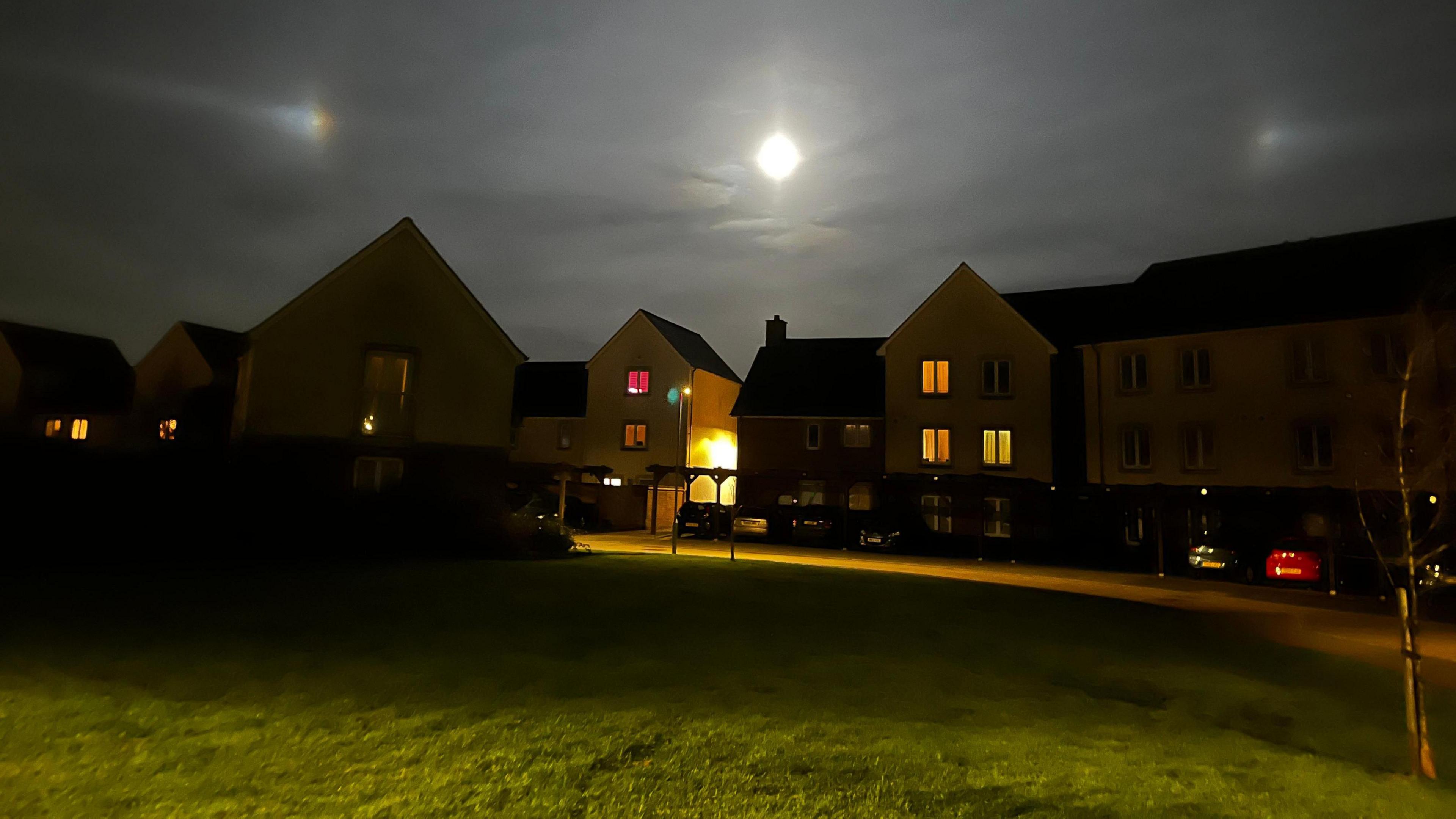 A row of houses with a bright illuminated moon with a 'halo effect' around it.