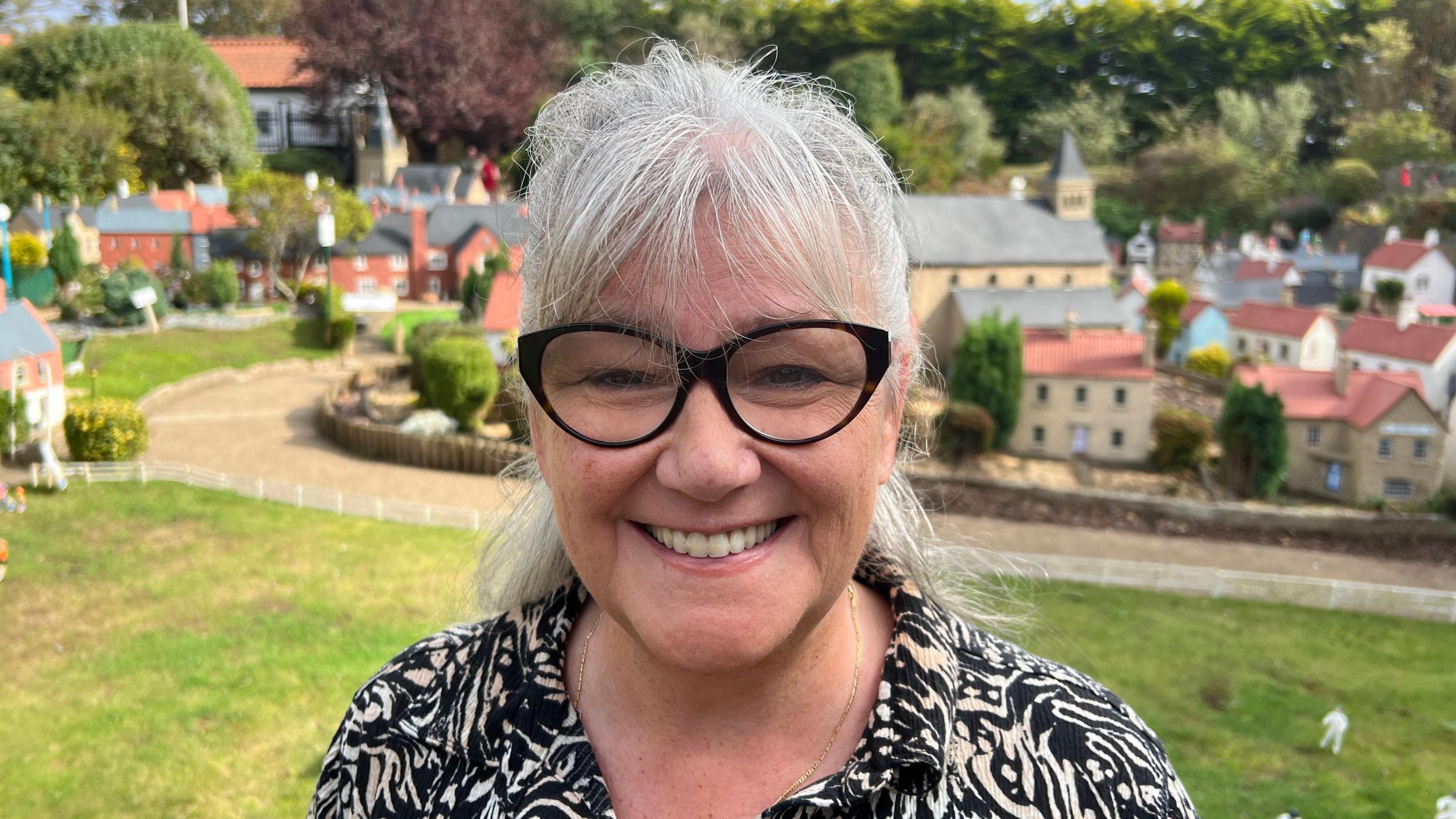 With a broad smile and black cats eye glasses, screenwriter Jan Birley has her silver hair tied back as she stands beside the miniature cricket ground at Bondville Model Village.