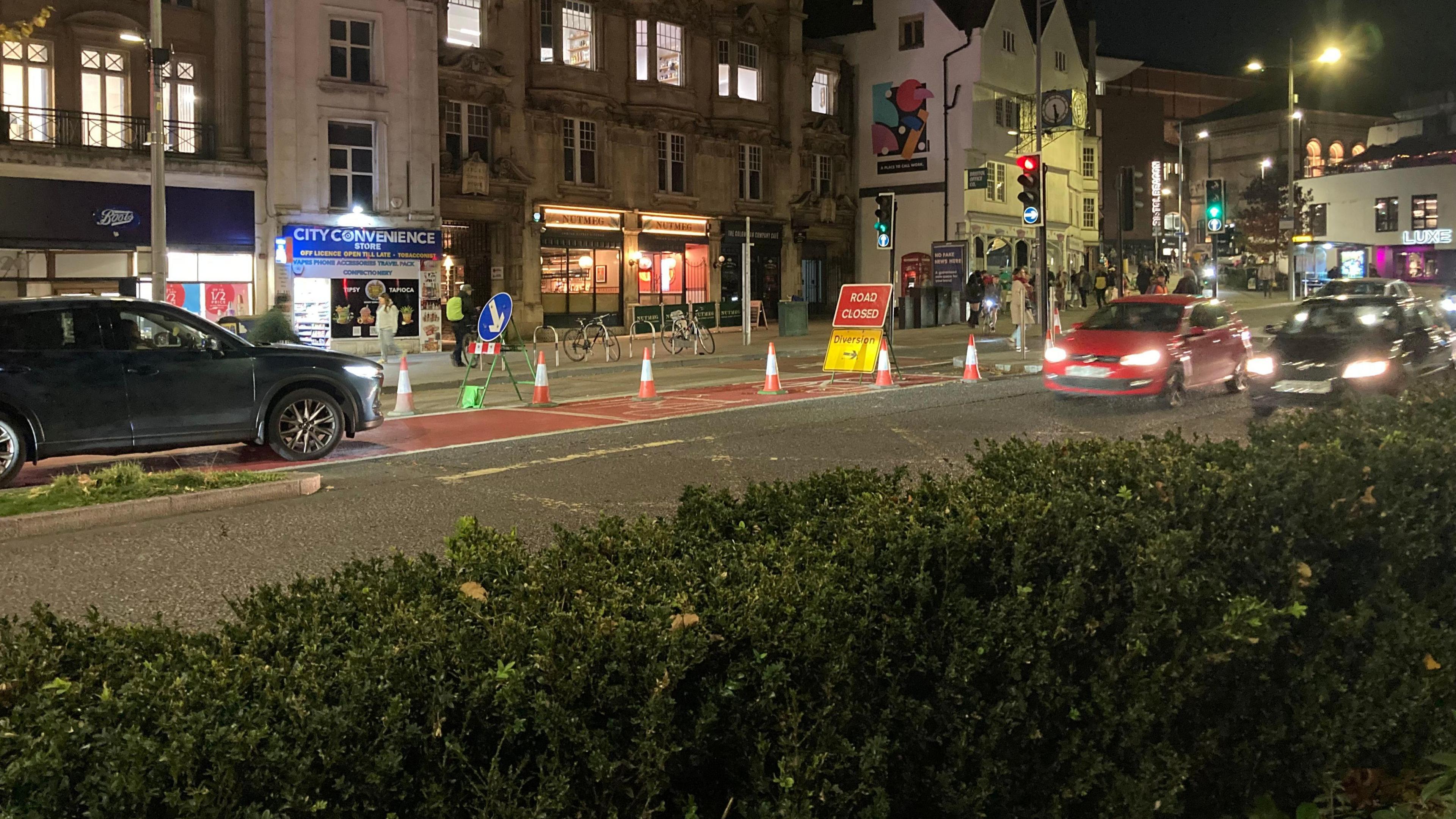 Traffic drives around a road closure in the city centre at night