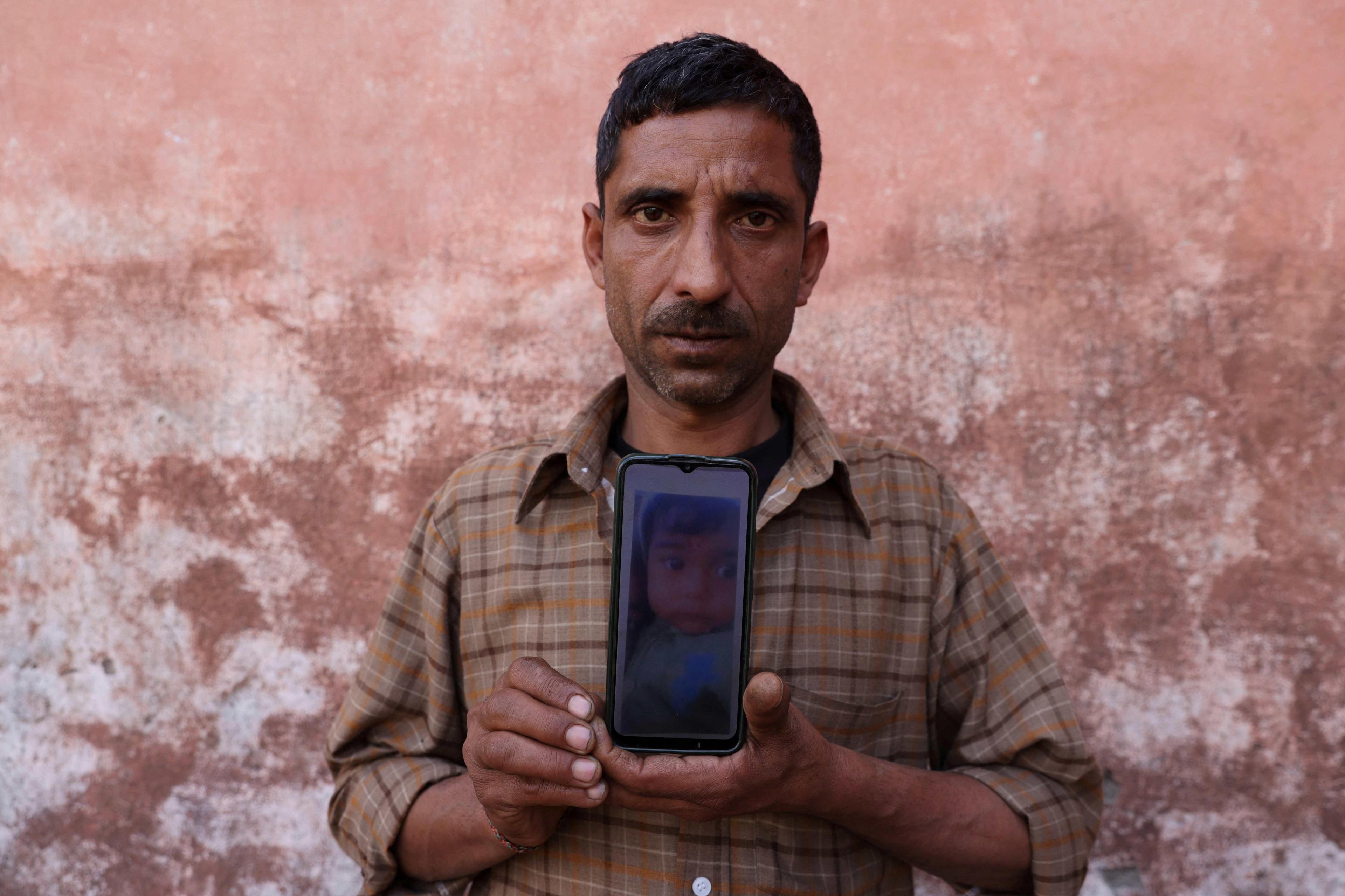 Govind Ram shows a picture, on his phone, of his daughter Surbhi Sharma, 3, who along with other children died due to kidney injury after consuming contaminated cough syrup in Jammu between December 2019 and January 2020, near a park in Ramnagar on the outskirts of Jammu, India, March 28, 2023. REUTERS/Anushree Fadnavis