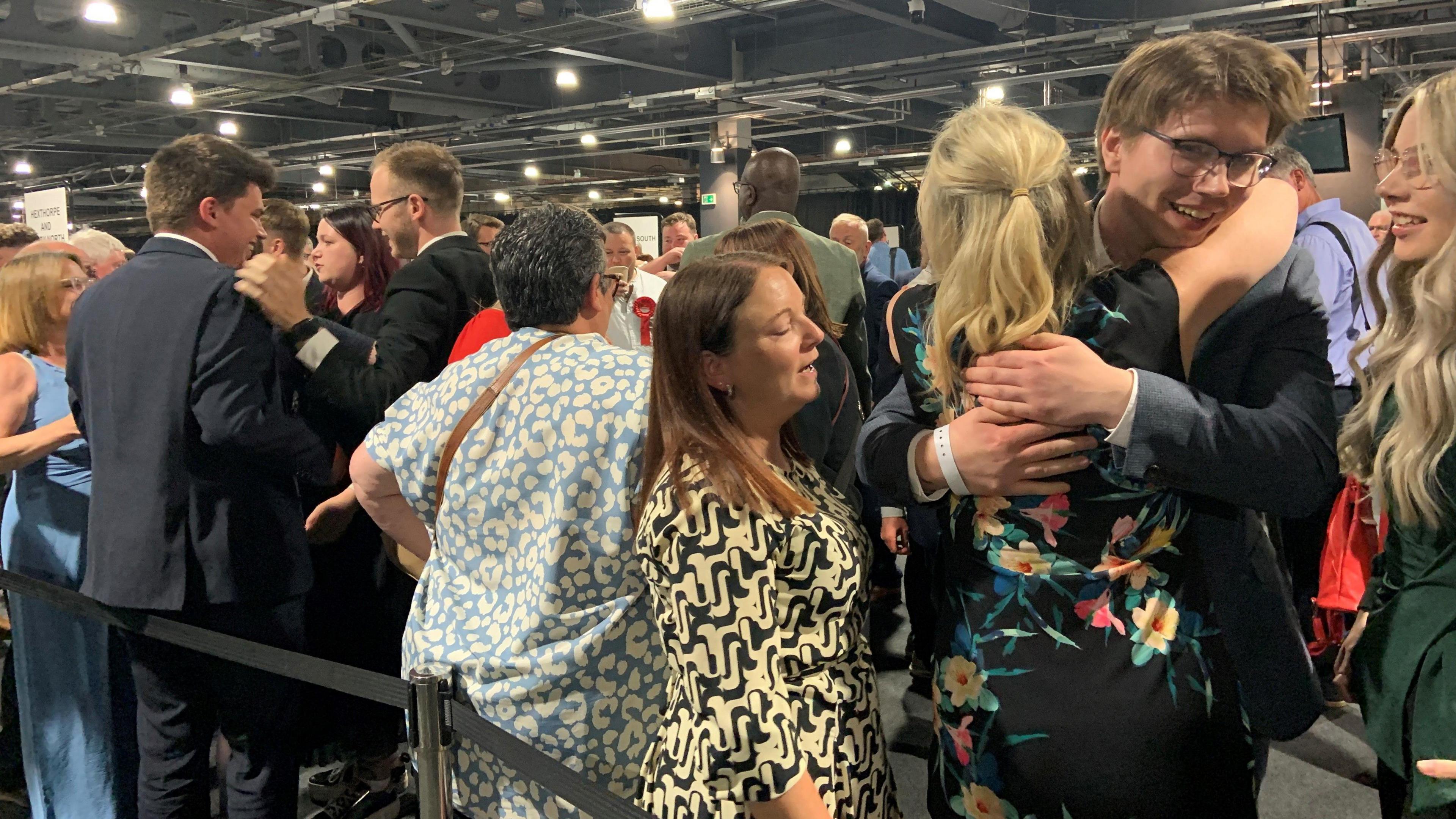 A crowd of people at a count are hugging and cheering
