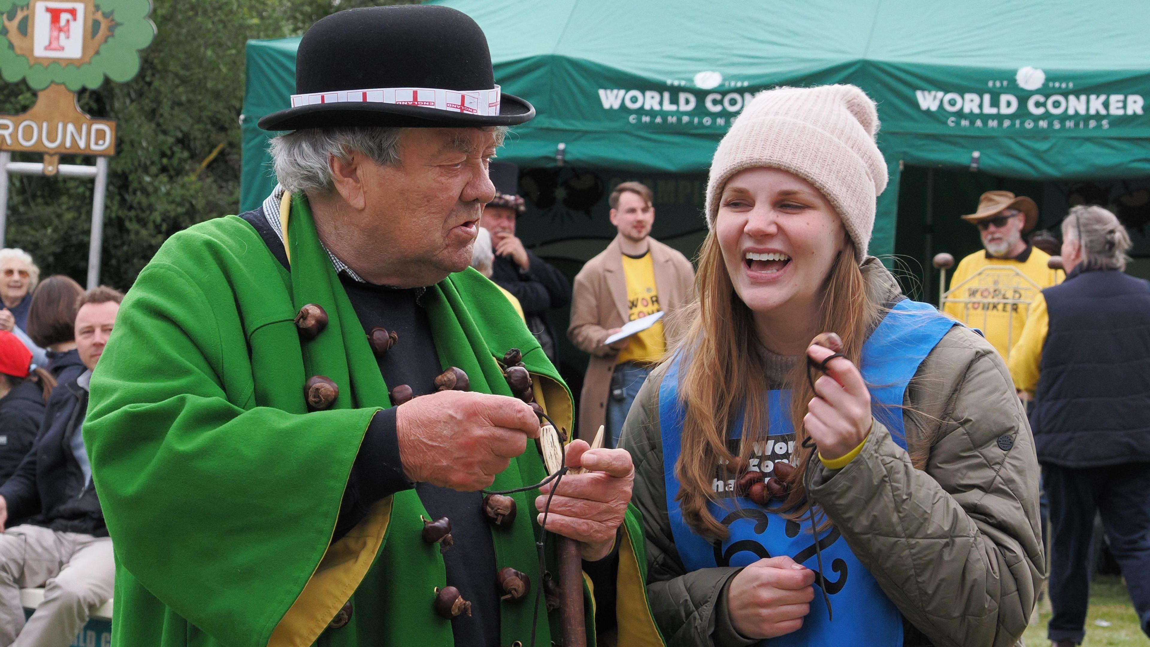 David Jakins and Kelci Banschbach are both holding their conkers. David has a face of disbelief and Kelci is laughibng.