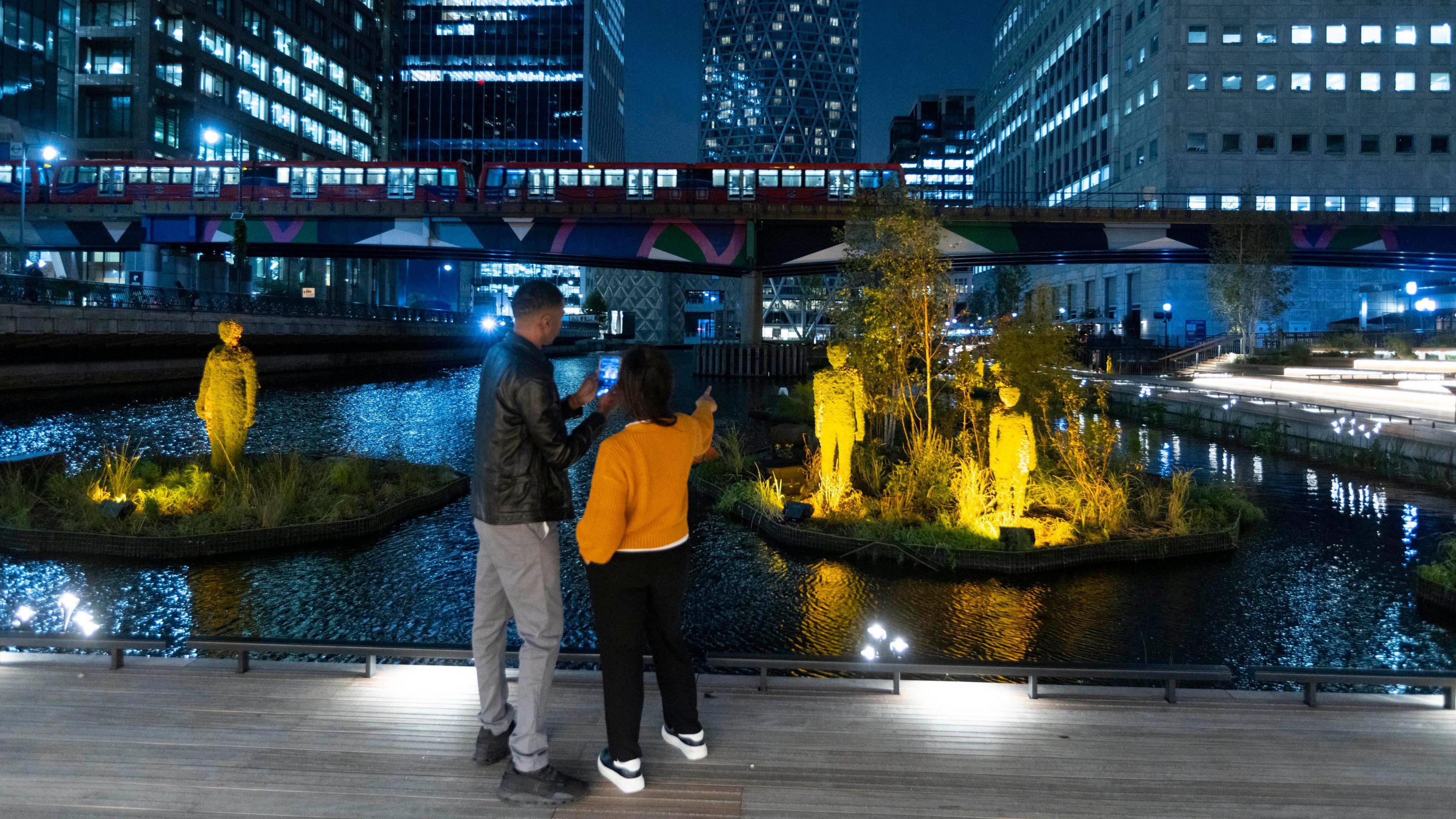 Couple looking at plant-filled island. The woman is pointing at it, directly in front of them