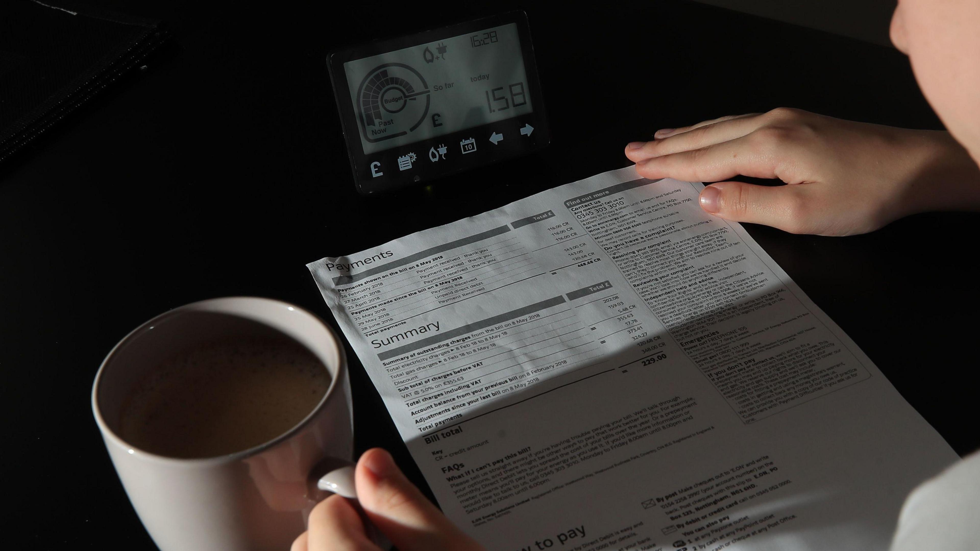 image of somebody looking over an energy bill. A smart meter can be seen in front of them.