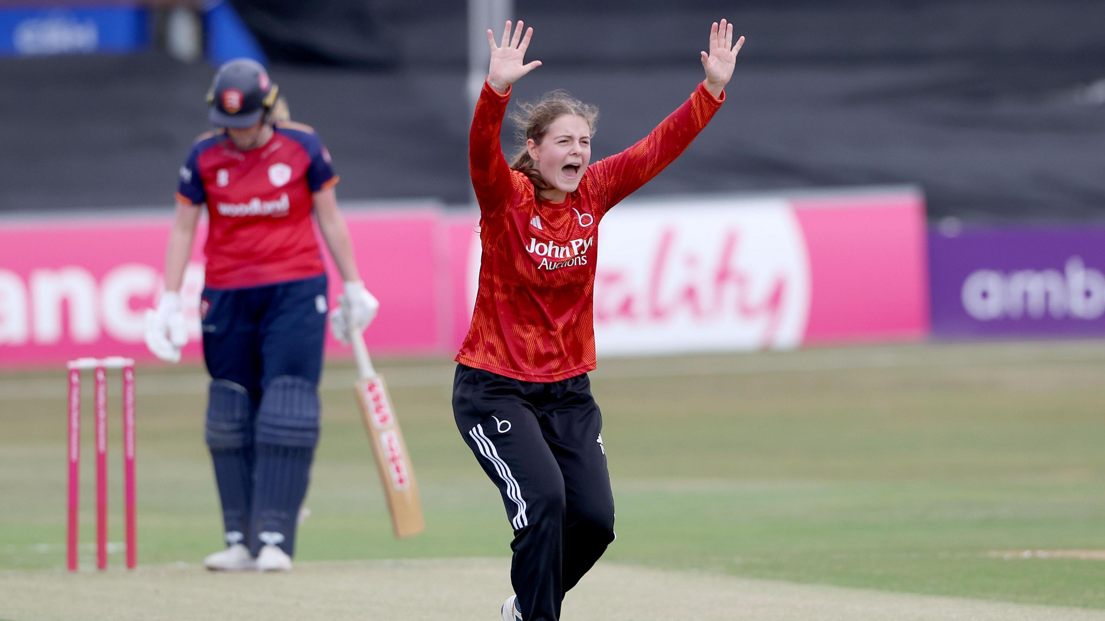 Maria Andrews of the Blaze appeals for the wicket of an Essex player (who can be seen in the background). Andrews is wearing a long-sleeve Blaze 2026 T20 shirt. 