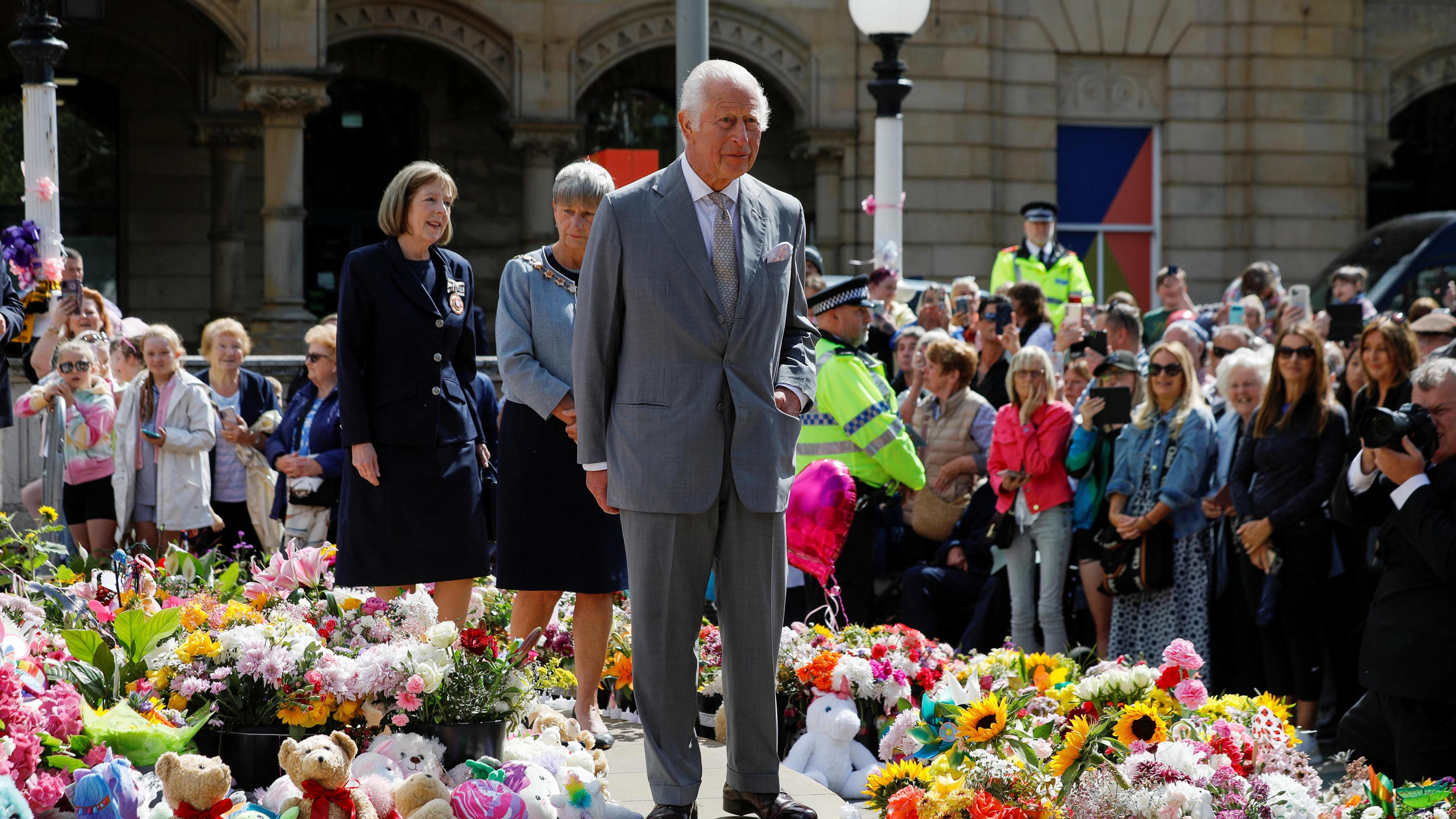 King Charles stands next to tributes, on the day of his community visit, outside the Town Hall in Southport