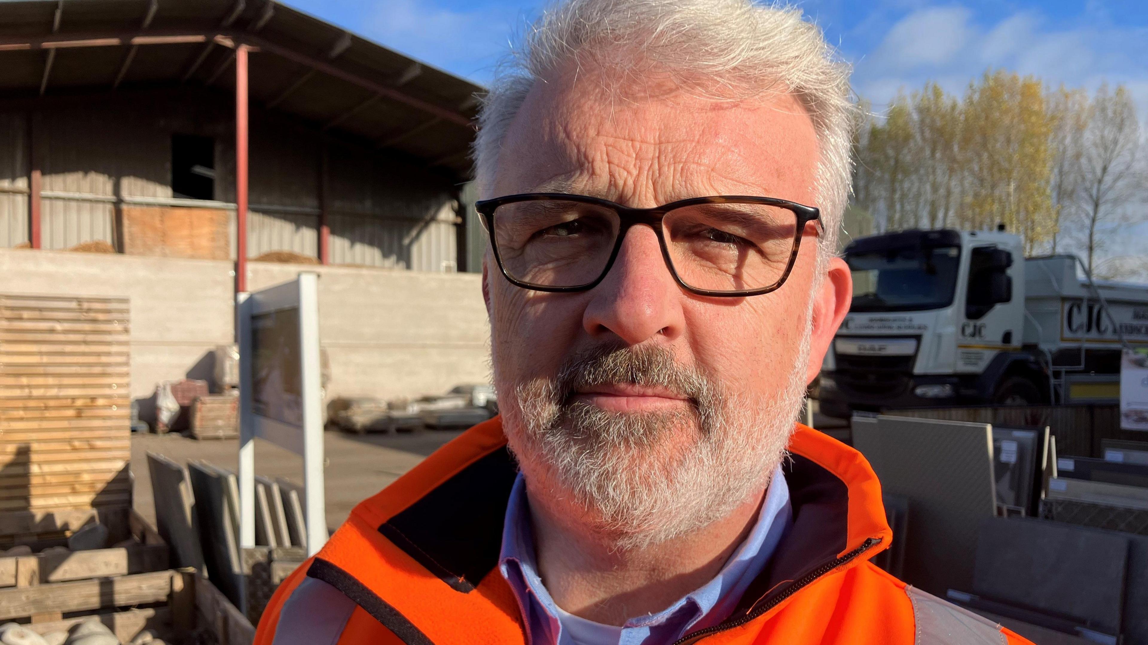 Richard Sadler looks at the camera on a sunny day at his firm's supply yard near Worcester.