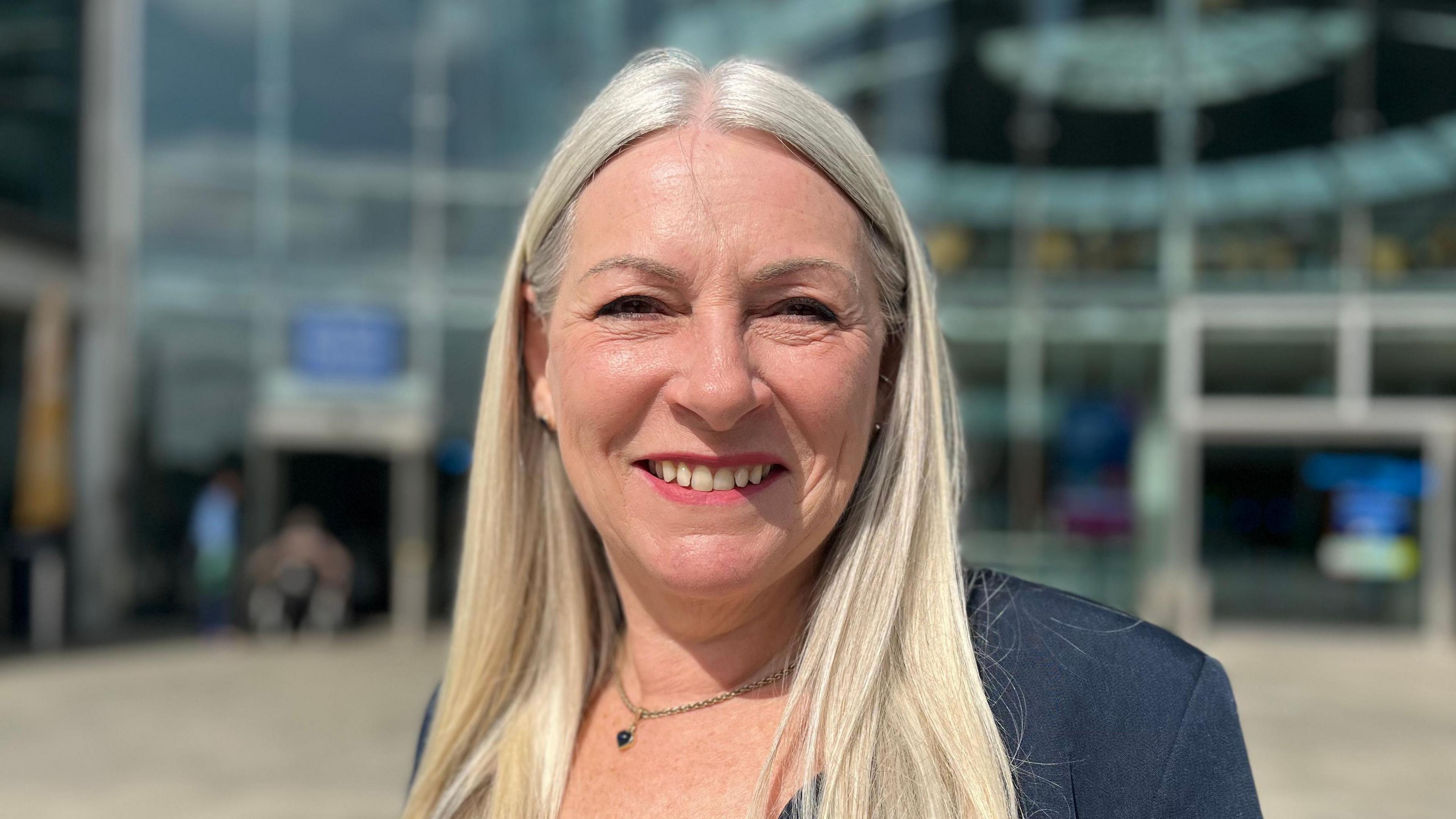 Norfolk County Council leader Kay Mason Billig standing outside The Forum in Norwich, smiling at the camera.