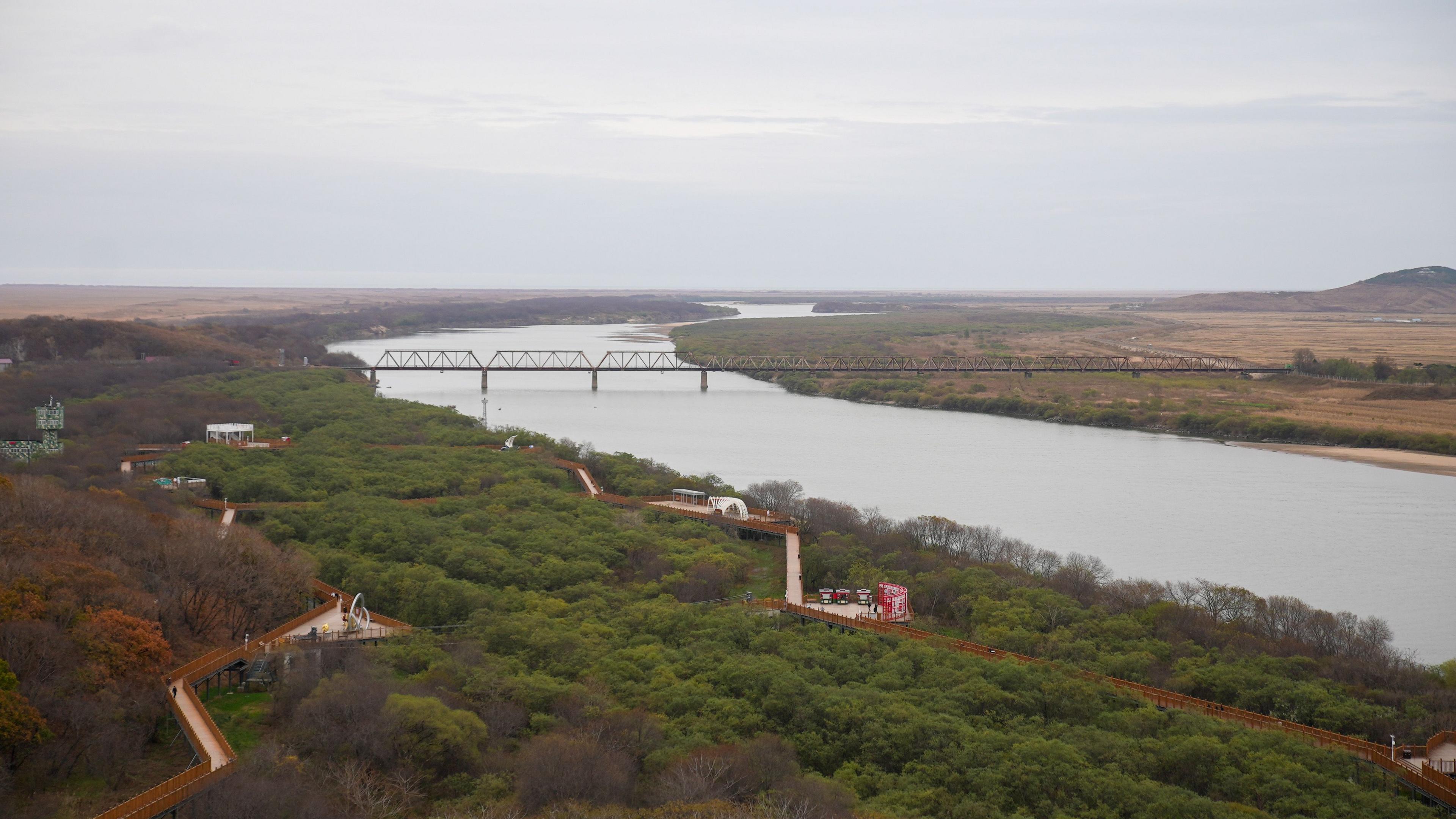 The friendship bridge connecting Russia and North Korea over a grey winding river. 