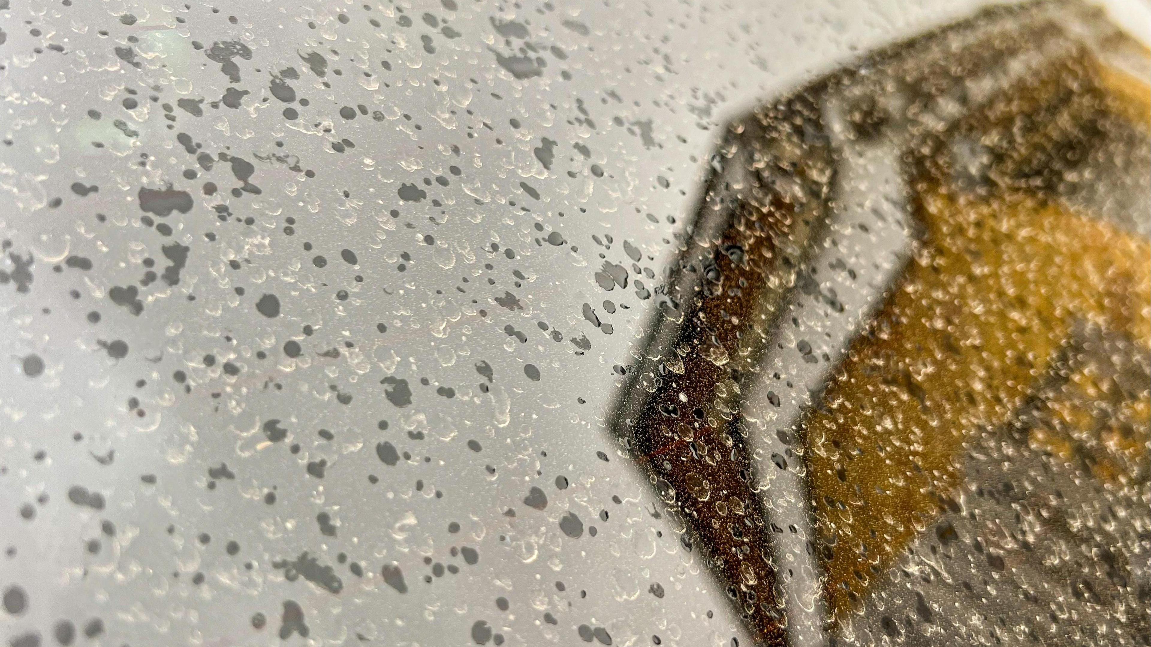 Shiny surface with evidence of rain with dust left behind where rain had dried