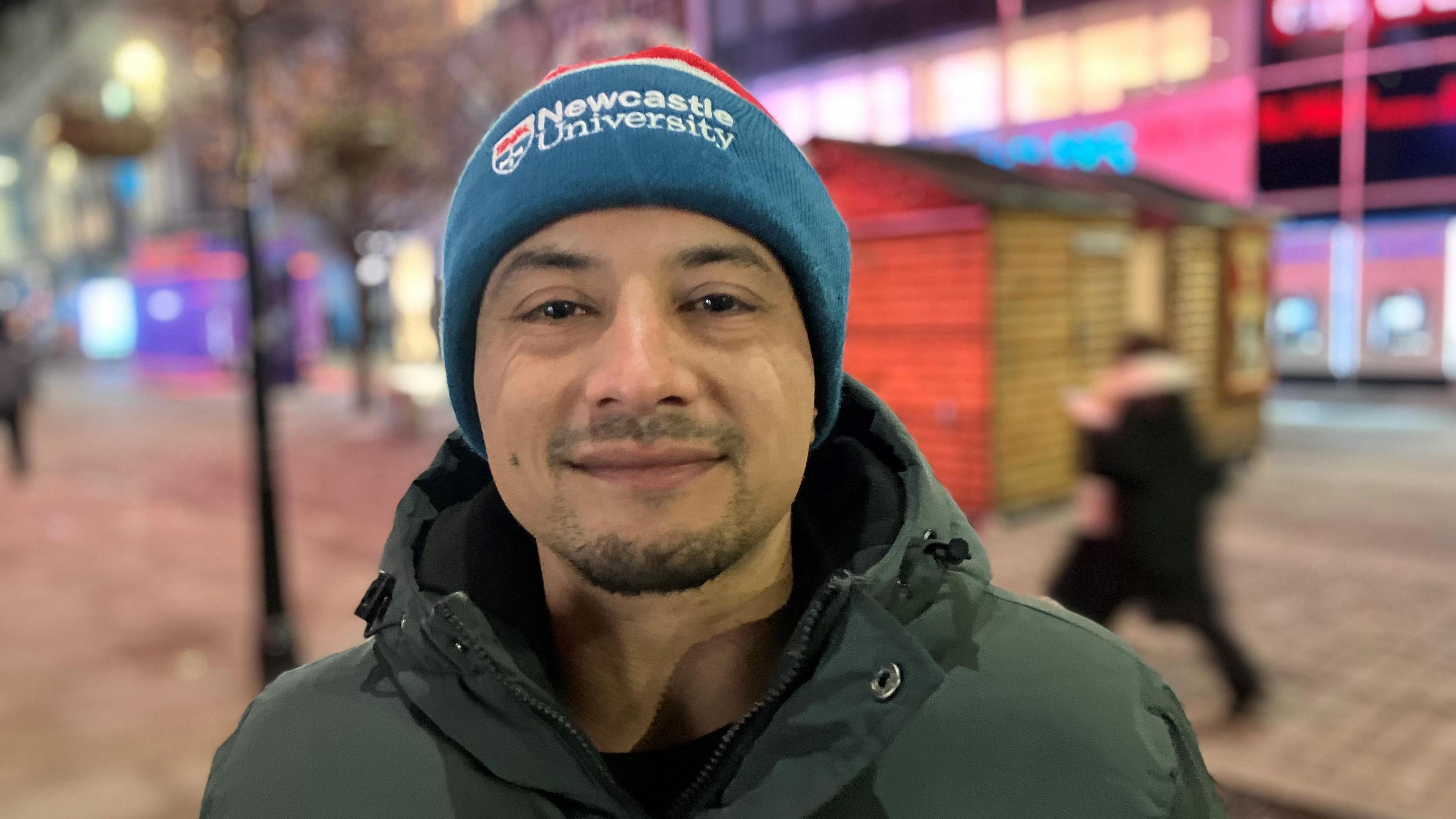Photograph of homelsss man Haroon Asif from Oldham. He is pictured on Market Street in Manchester city centre wearing a coat and a hat.