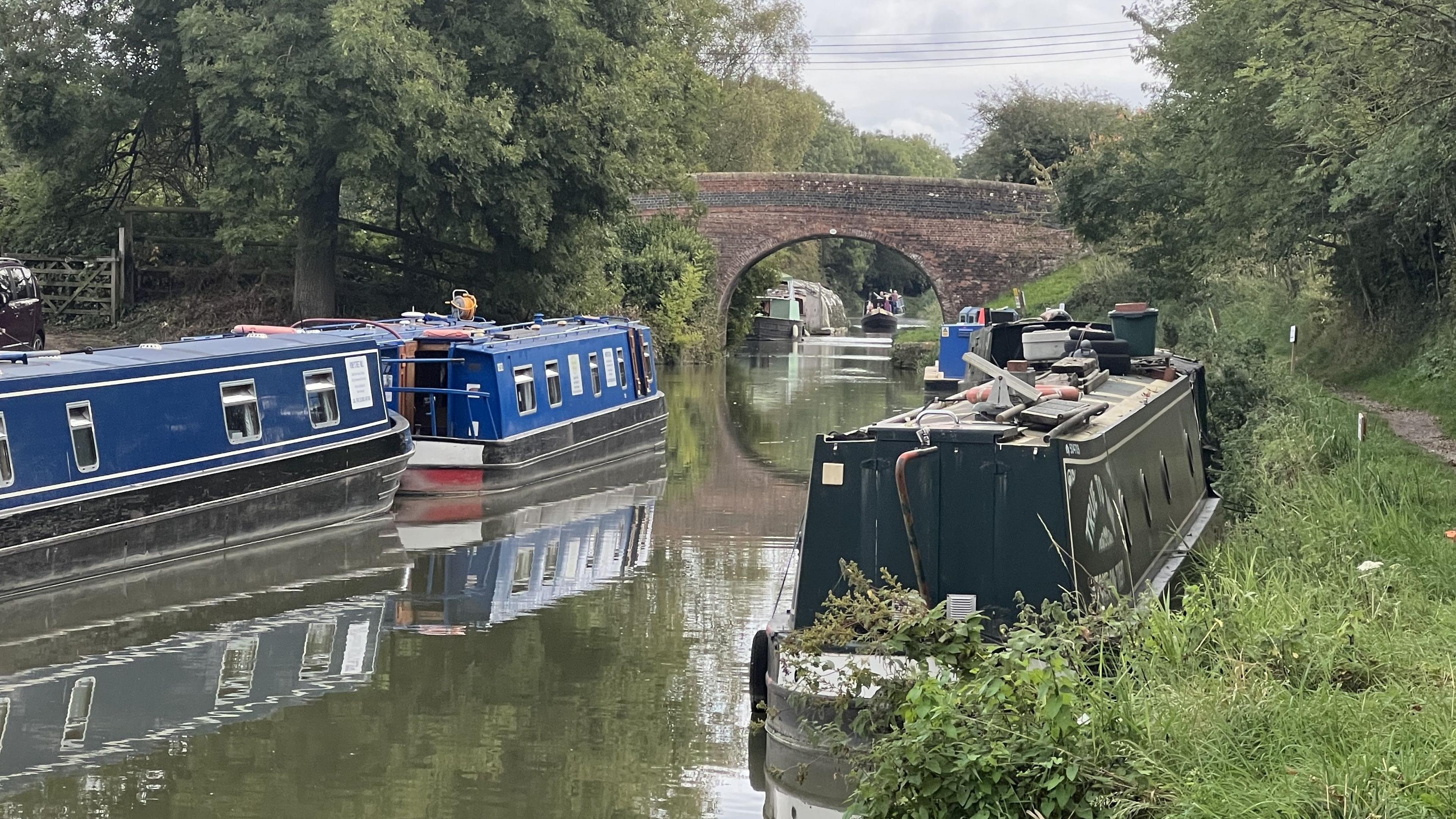 Canal boats moored on the Kennet and Avon canal with a bridge in the background