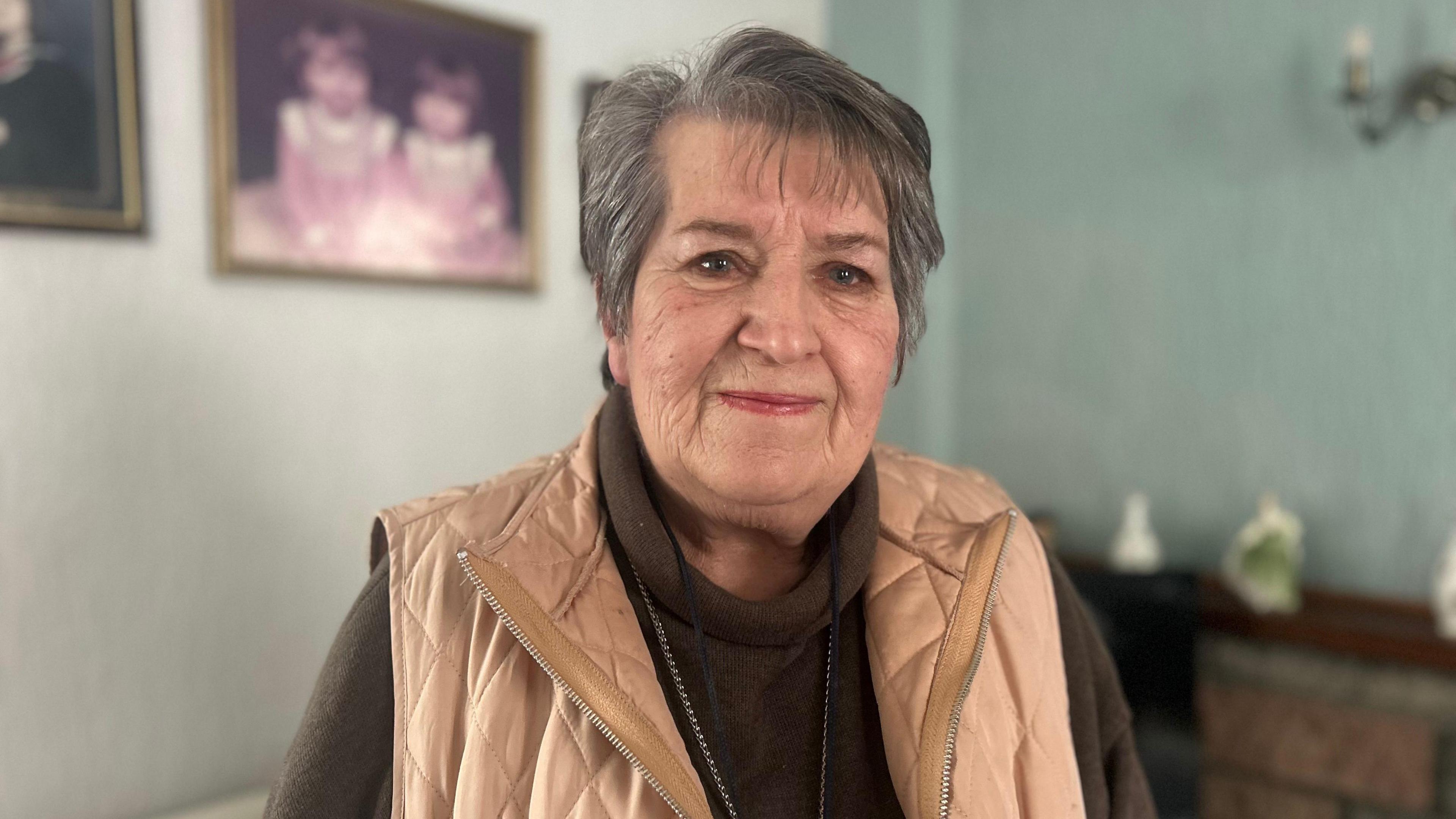 Rosalynd Davies mewn siwmper brown a siaced brown golau