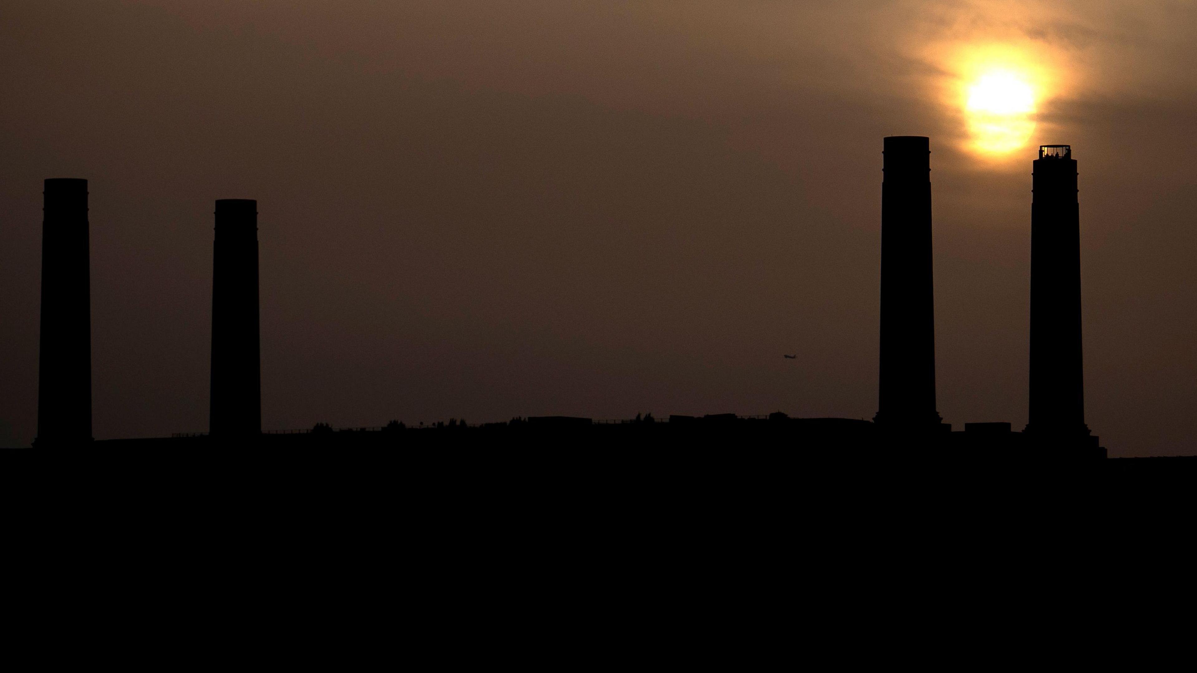 The four chimneys of Battersea Power station silhouetted against an orangey sky 