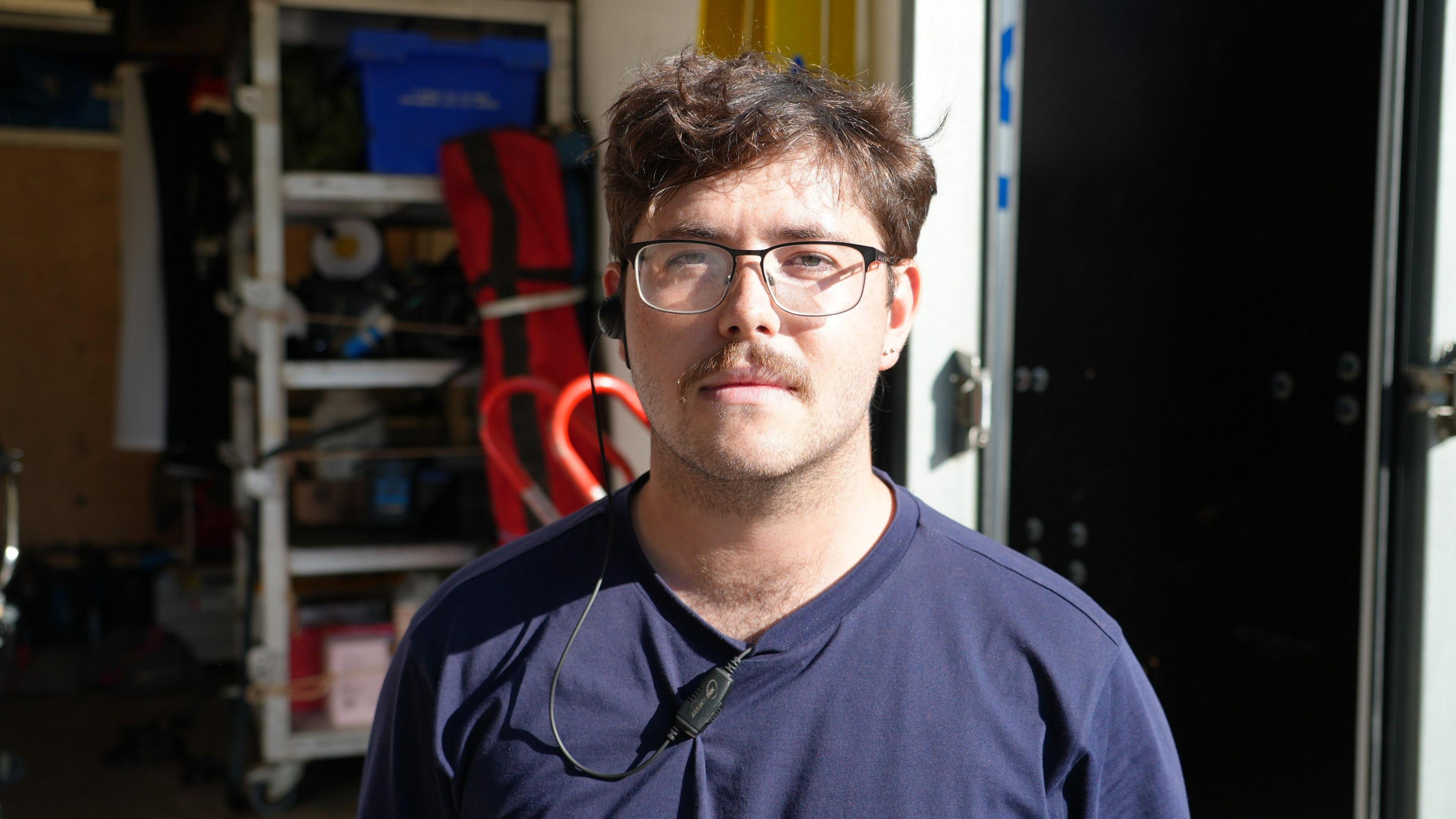 Young man standing in front of lorry filled with electrical equipment 