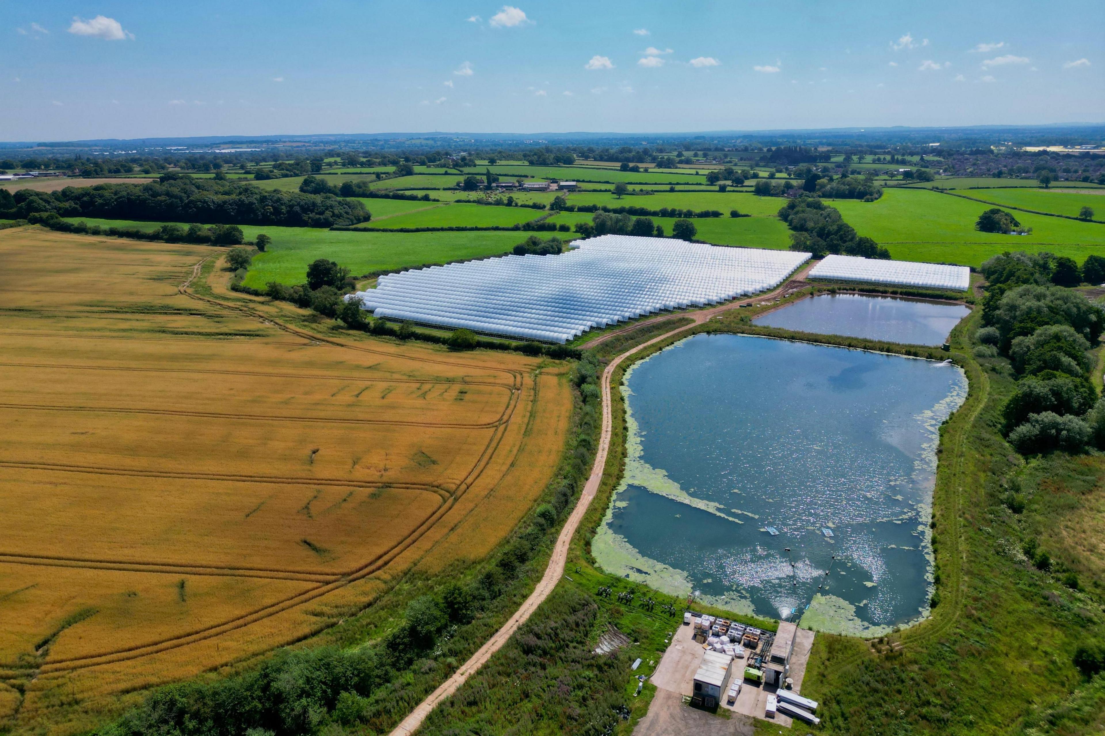 Drone's eye view of fields in Gnosall, showing farmland and a large pool